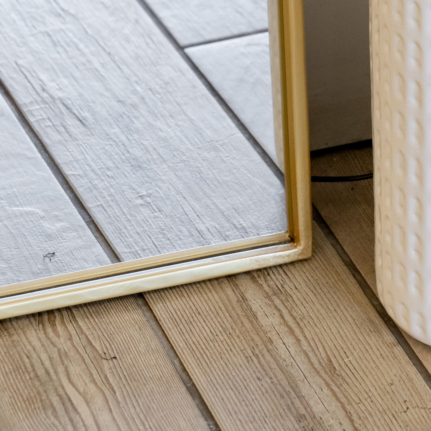 Gold-framed mirror edge resting on wooden floorboards.