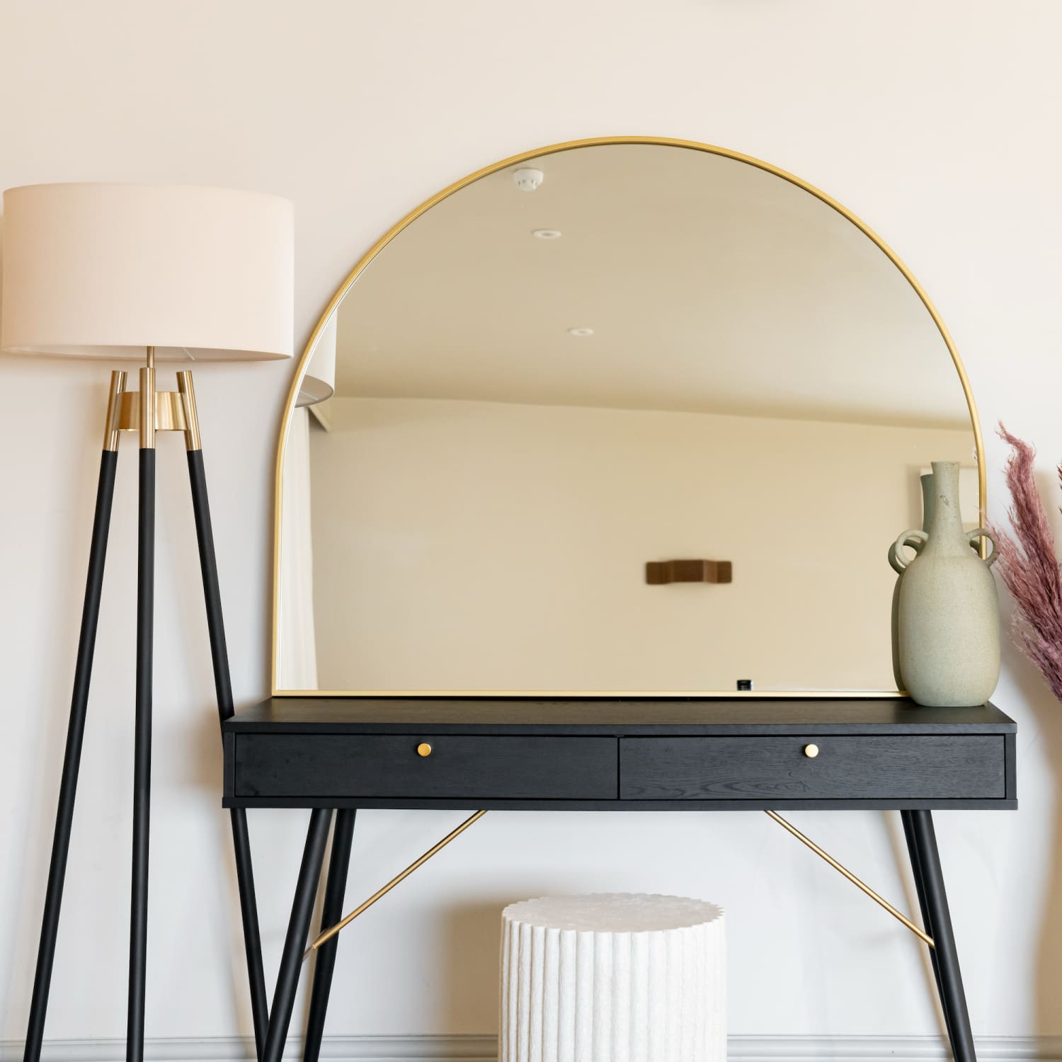 Modern vanity table with a round gold-rimmed mirror and black drawers.