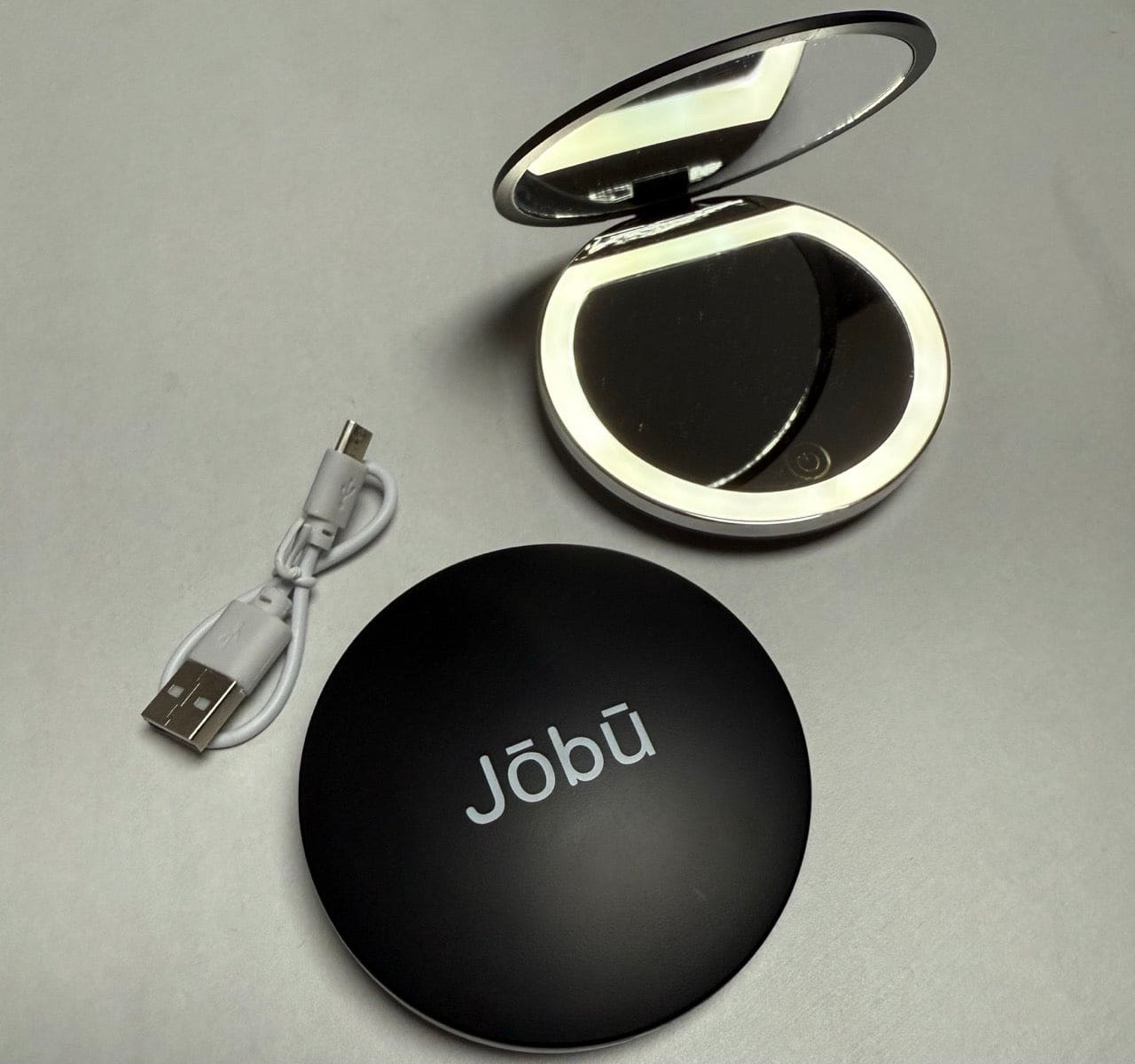 Black compact mirror with illuminated edge, usb charging cable included.