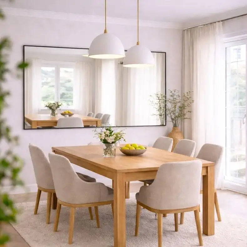 Light wood dining table with matching chairs and a large rectangular mirror above it