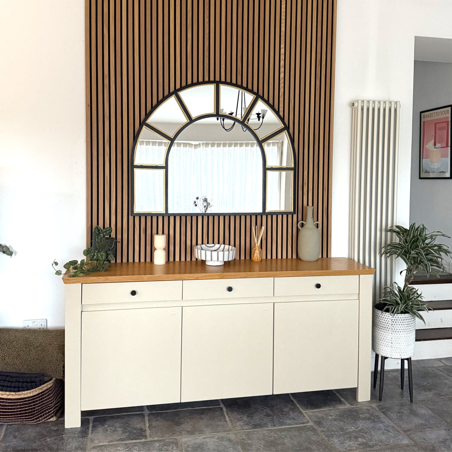Cream-colored sideboard with wooden top and three drawers above three cabinet doors.