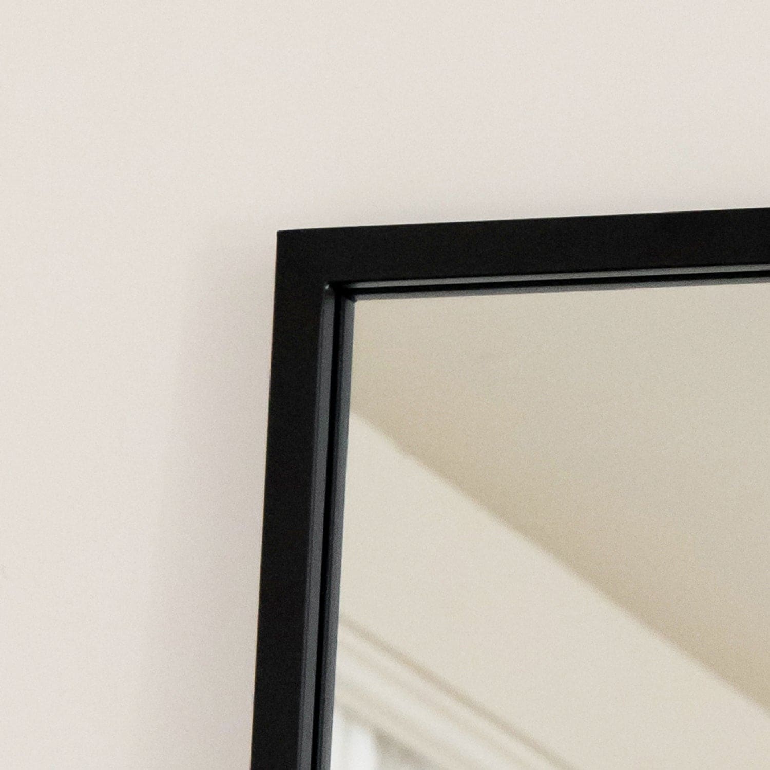 A black-framed mirror reflecting a light-colored interior.