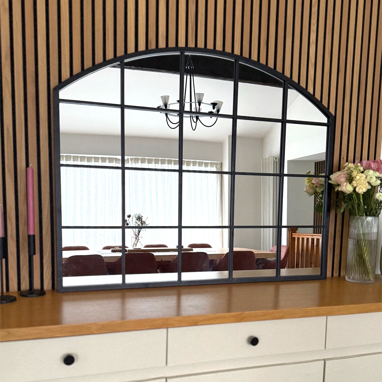 Arched window-style mirror with black grid pattern framing.