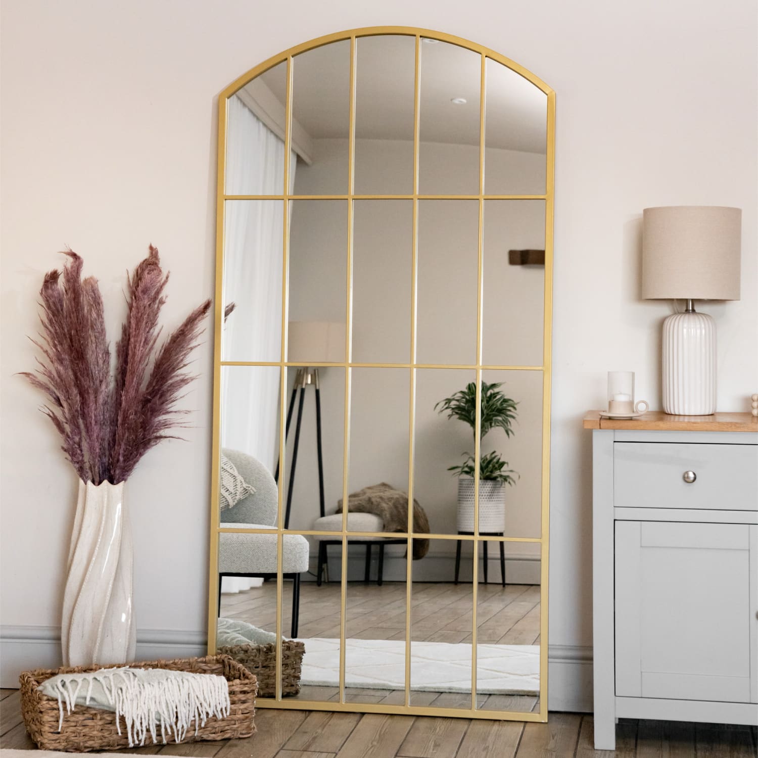 Arched gold-framed mirror with grid pattern dividers.