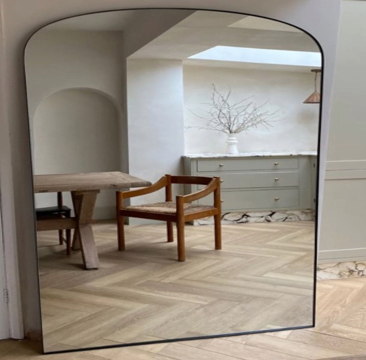 A full-length, arch-top mirror with a thin black frame.