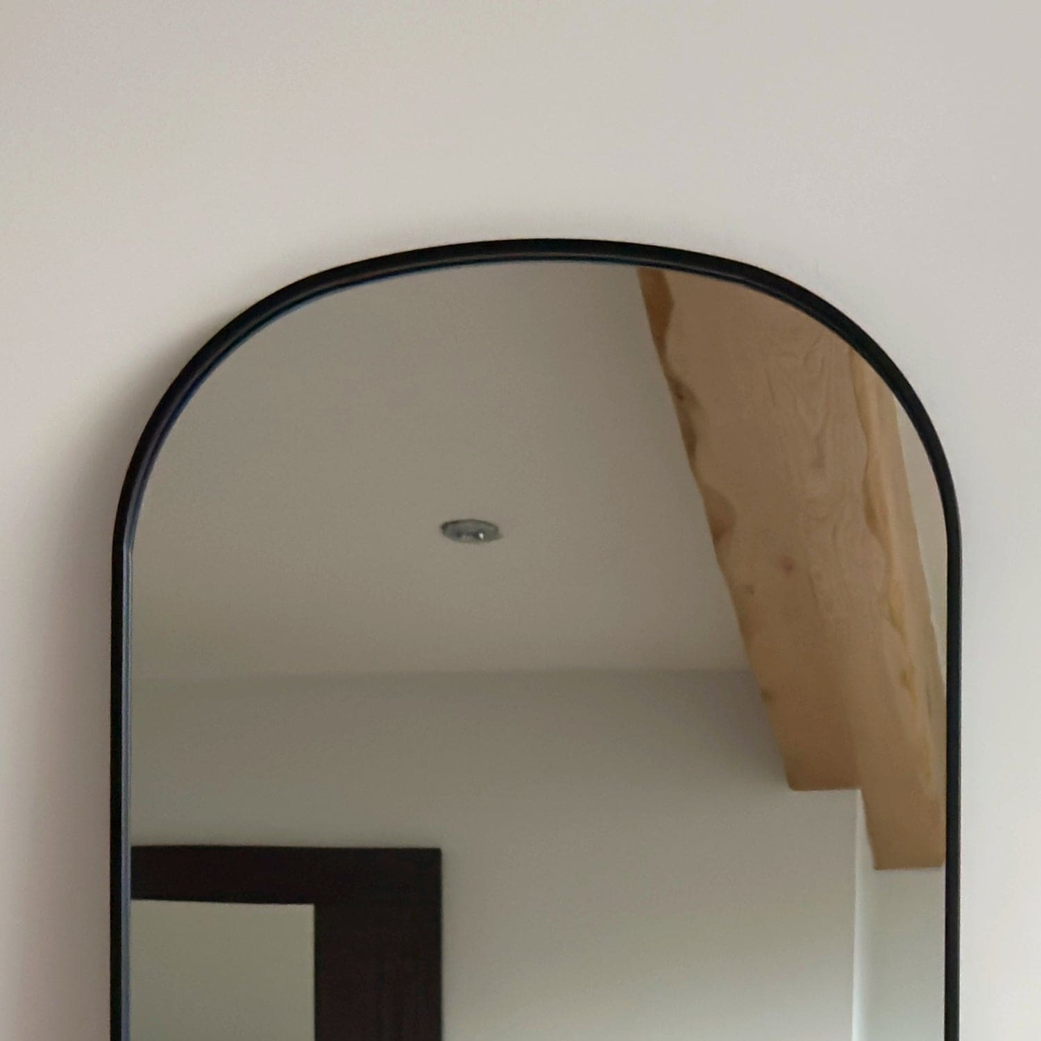 Arched mirror with a thin black metal frame.