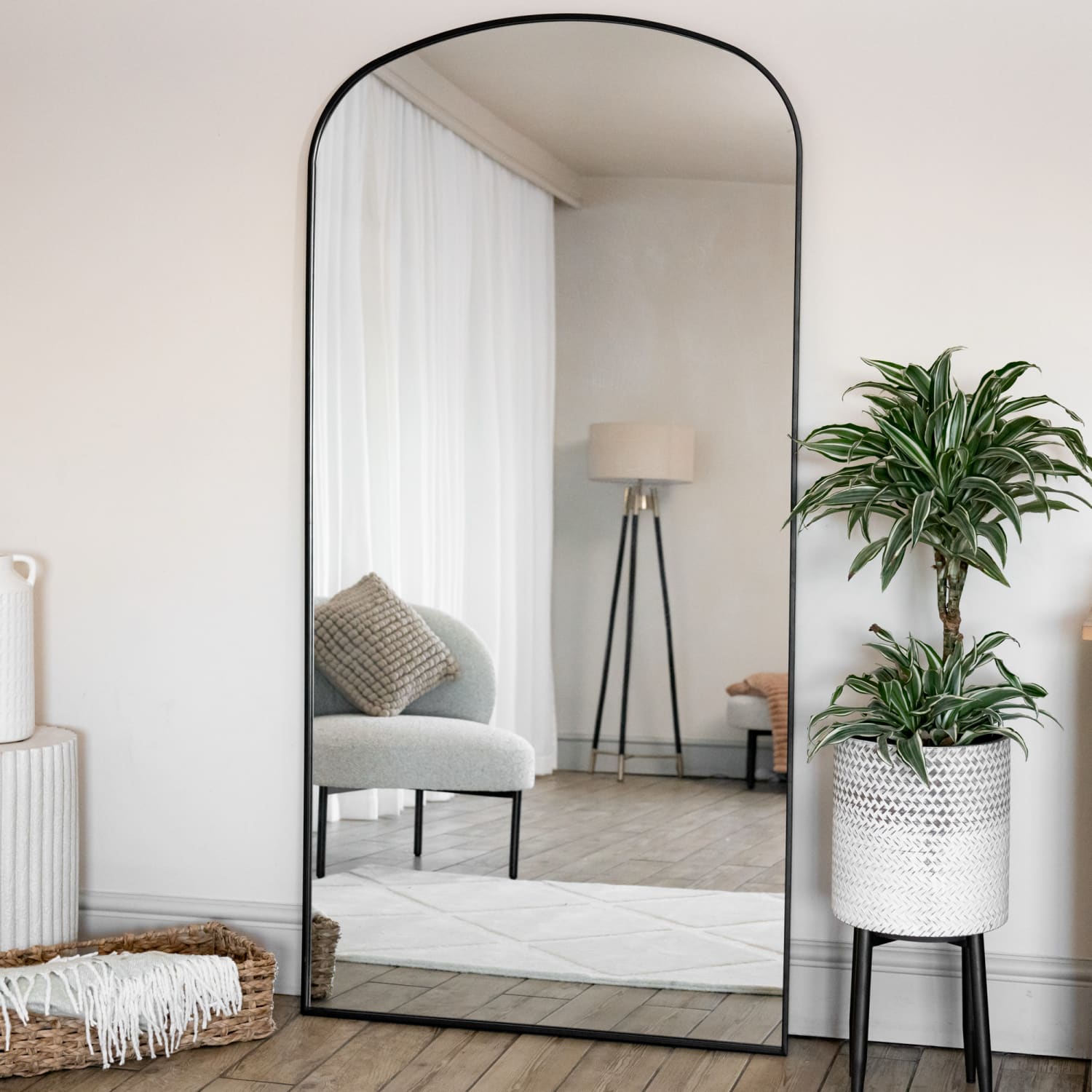 Arched floor mirror with thin black metal frame.