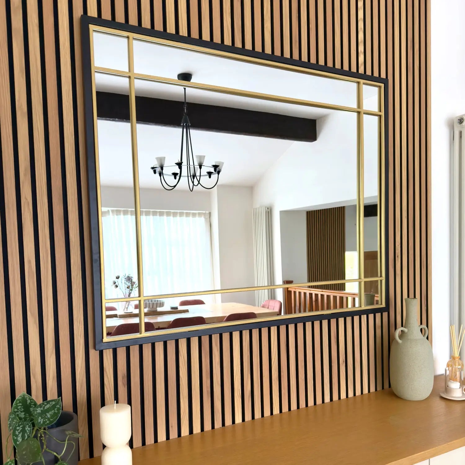 Gold-framed rectangular mirror mounted on a wood-slatted wall.