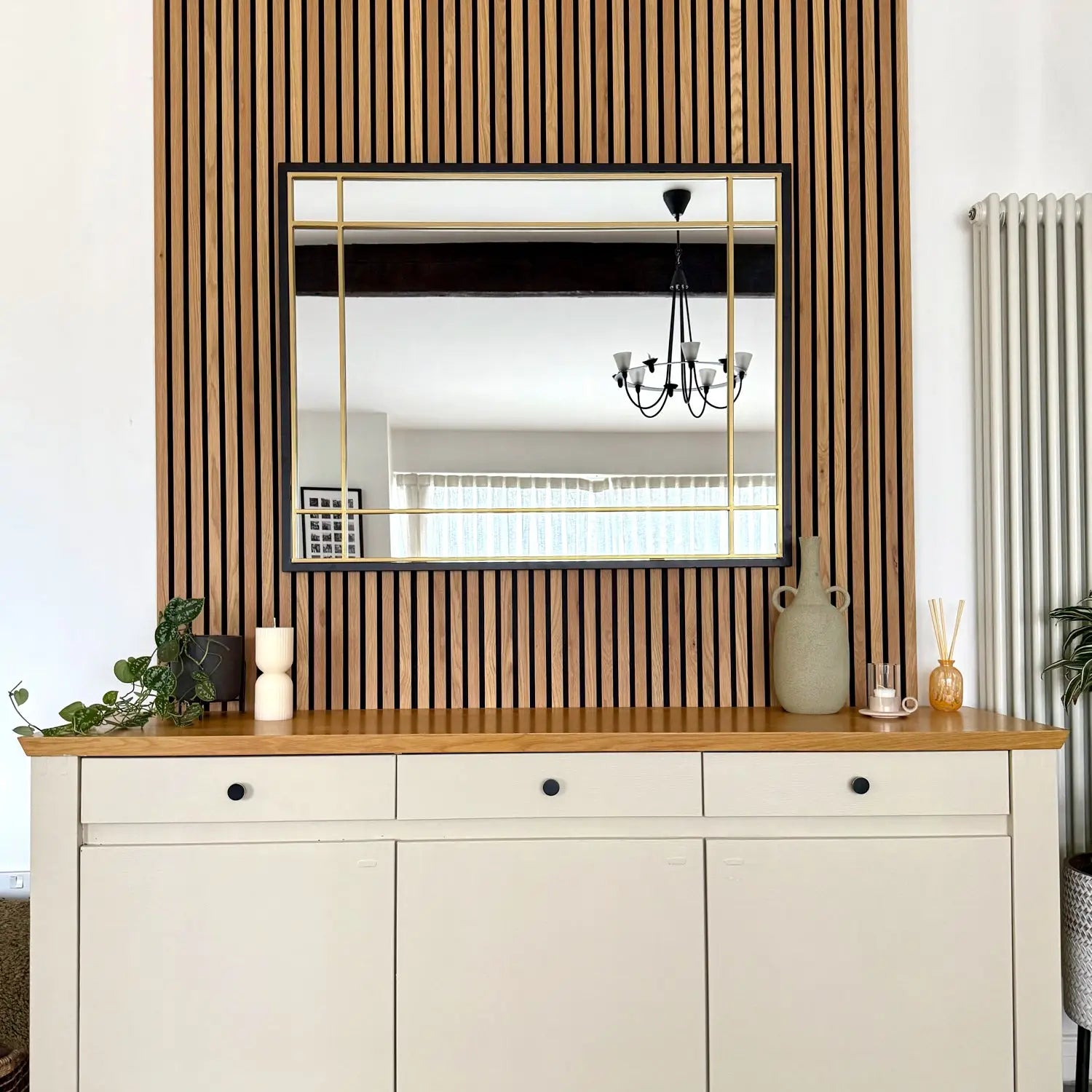 White credenza with wooden top and vertical slat wall accent behind it.