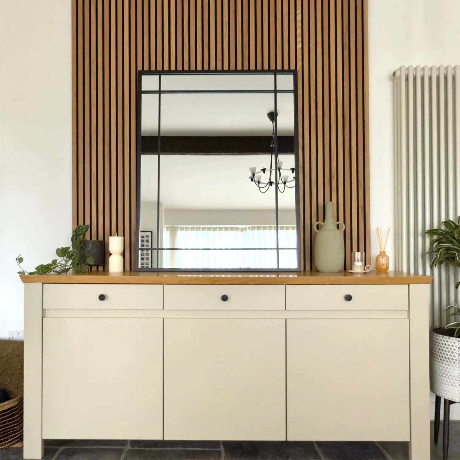 Cream-colored cabinet with wooden top and three drawers beneath a framed mirror.