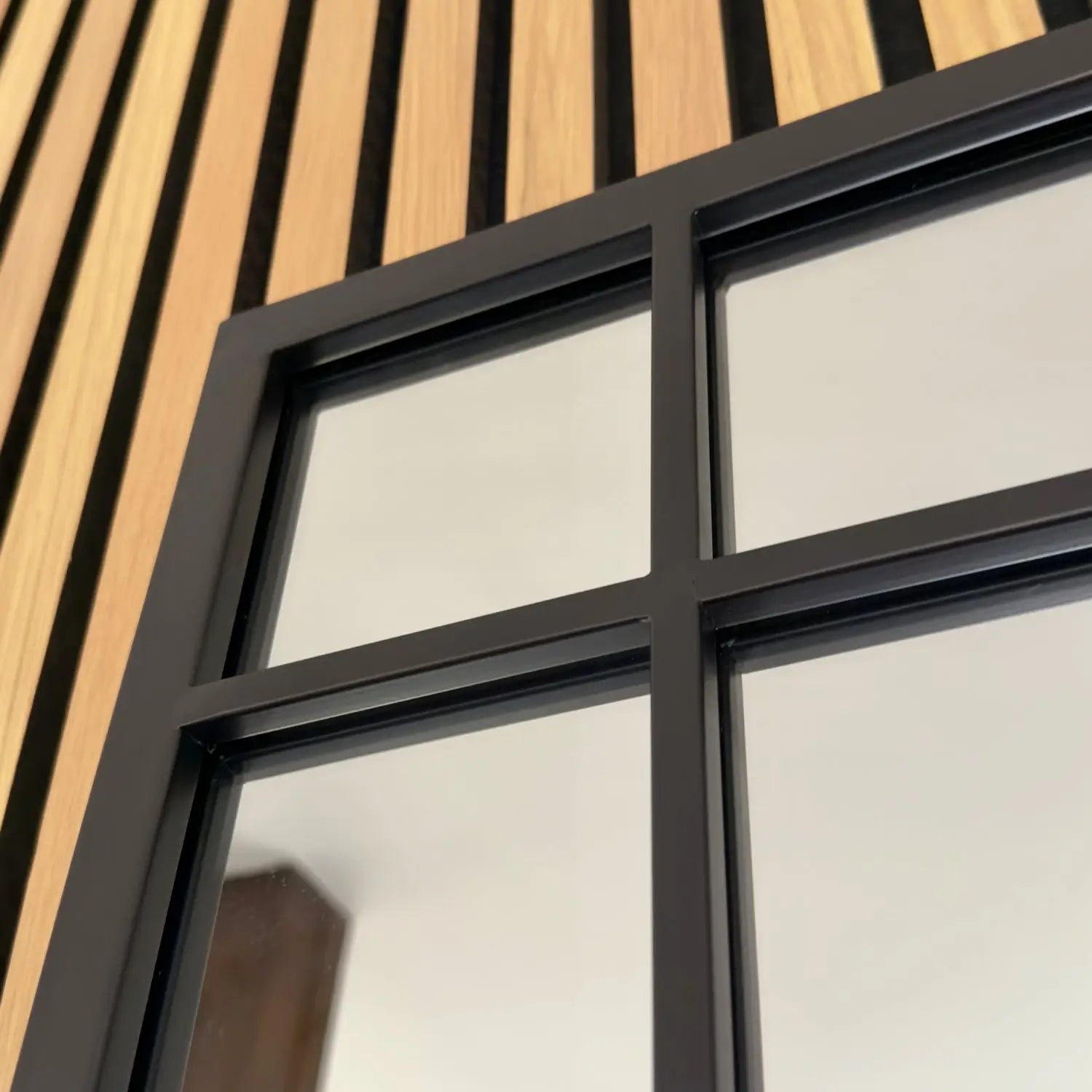 Black-framed window with four panes against wooden slats.