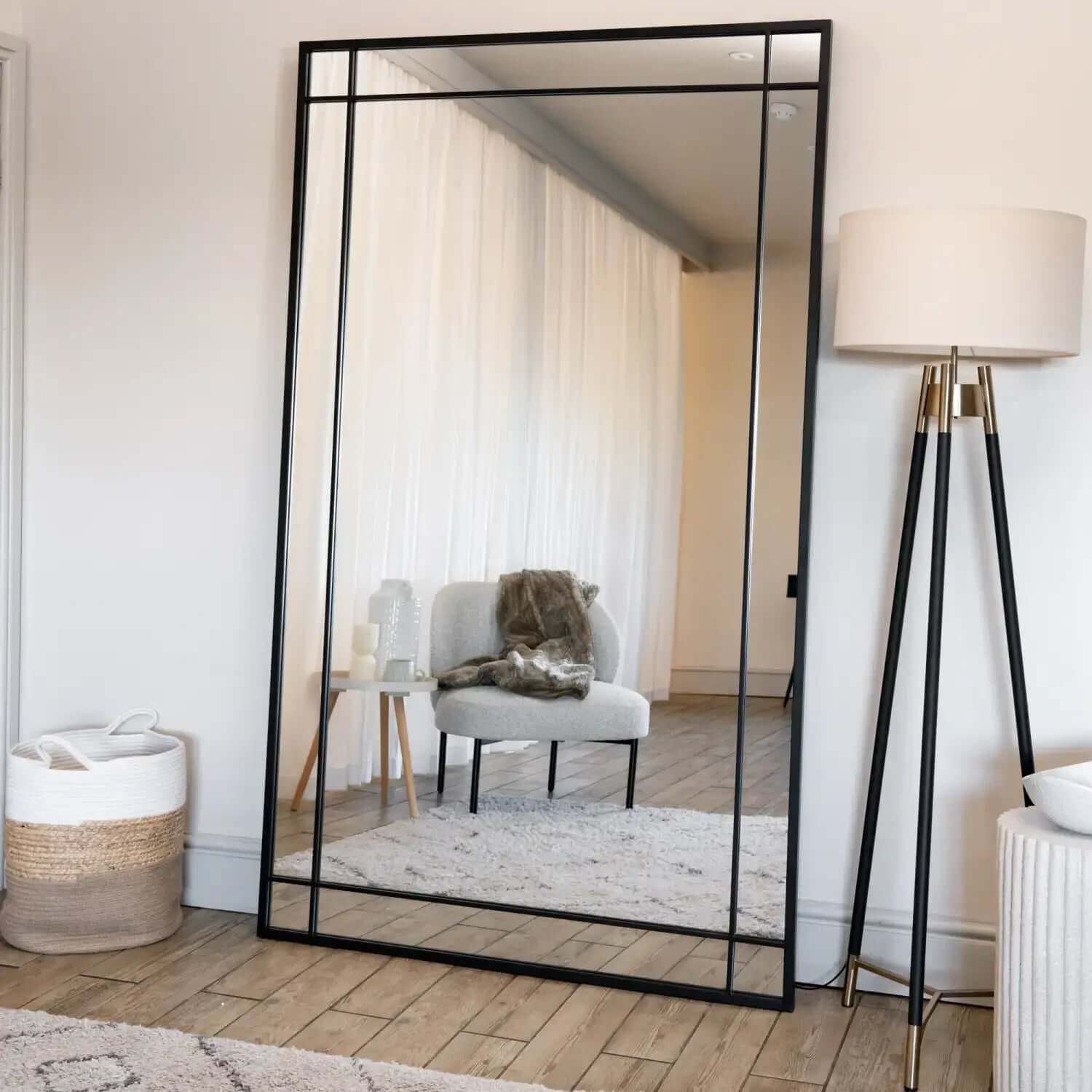 Black-framed rectangular floor mirror with geometric border design.