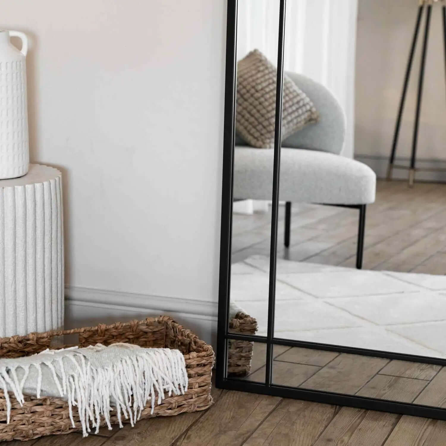 Black-framed floor mirror with geometric metal detailing.