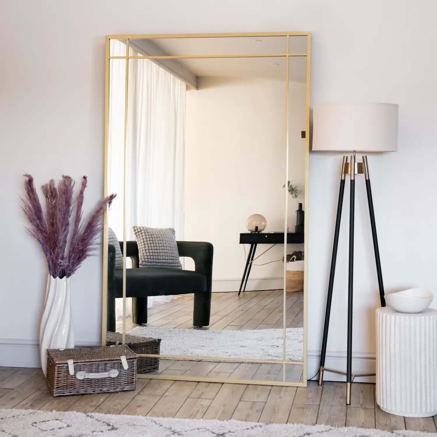 Gold-framed floor mirror with geometric grid pattern.