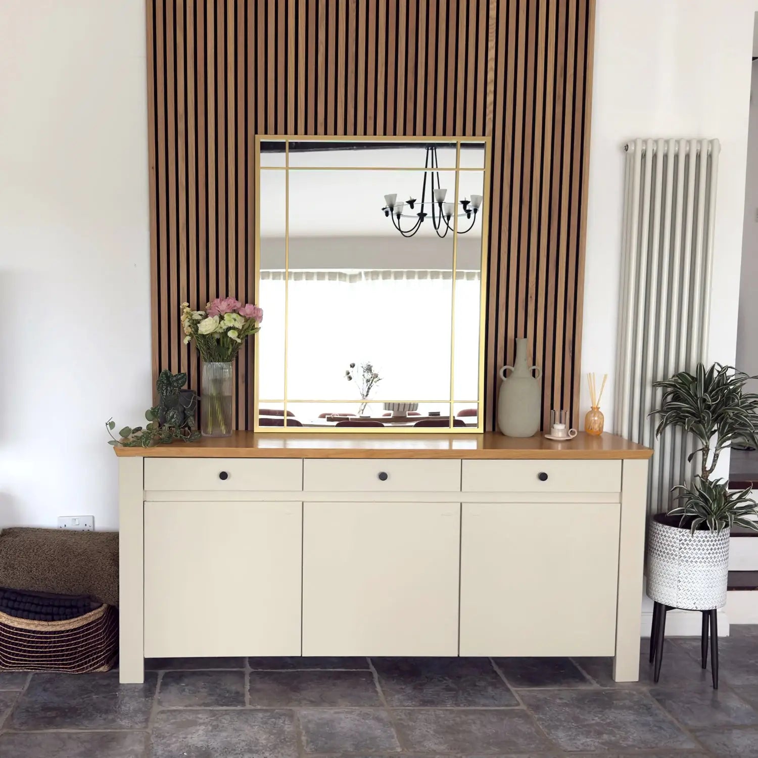 Cream-colored sideboard with wooden top and three drawers above three cabinet doors.