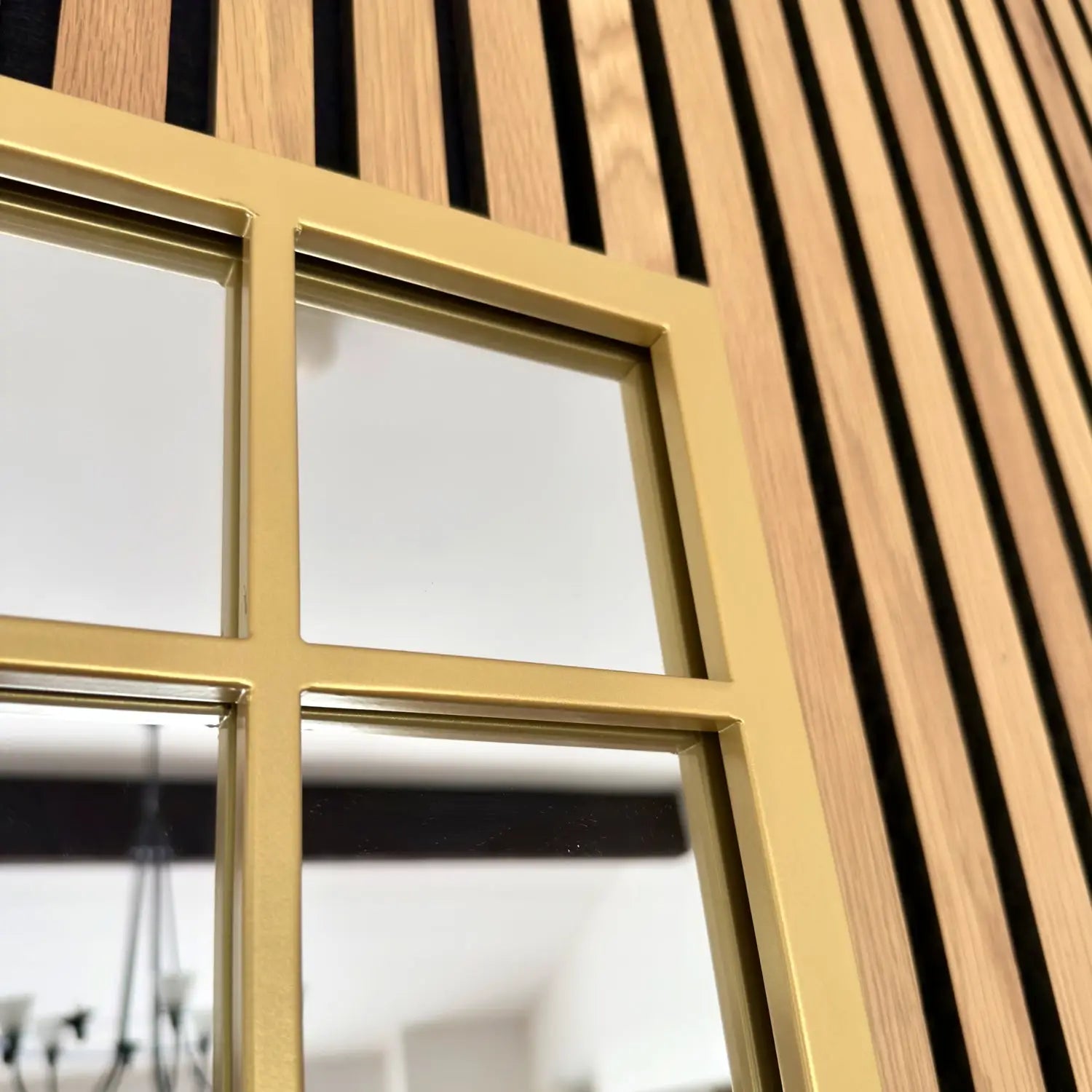 Window with gold-colored frame and vertical wooden slats alongside it.