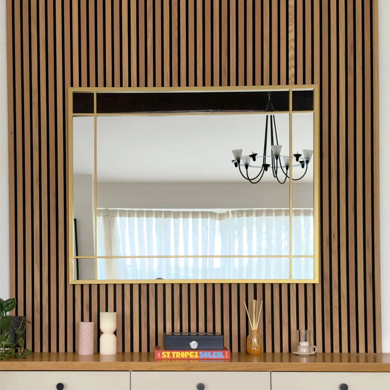 Gold-framed rectangular mirror mounted on a wood-slatted wall.