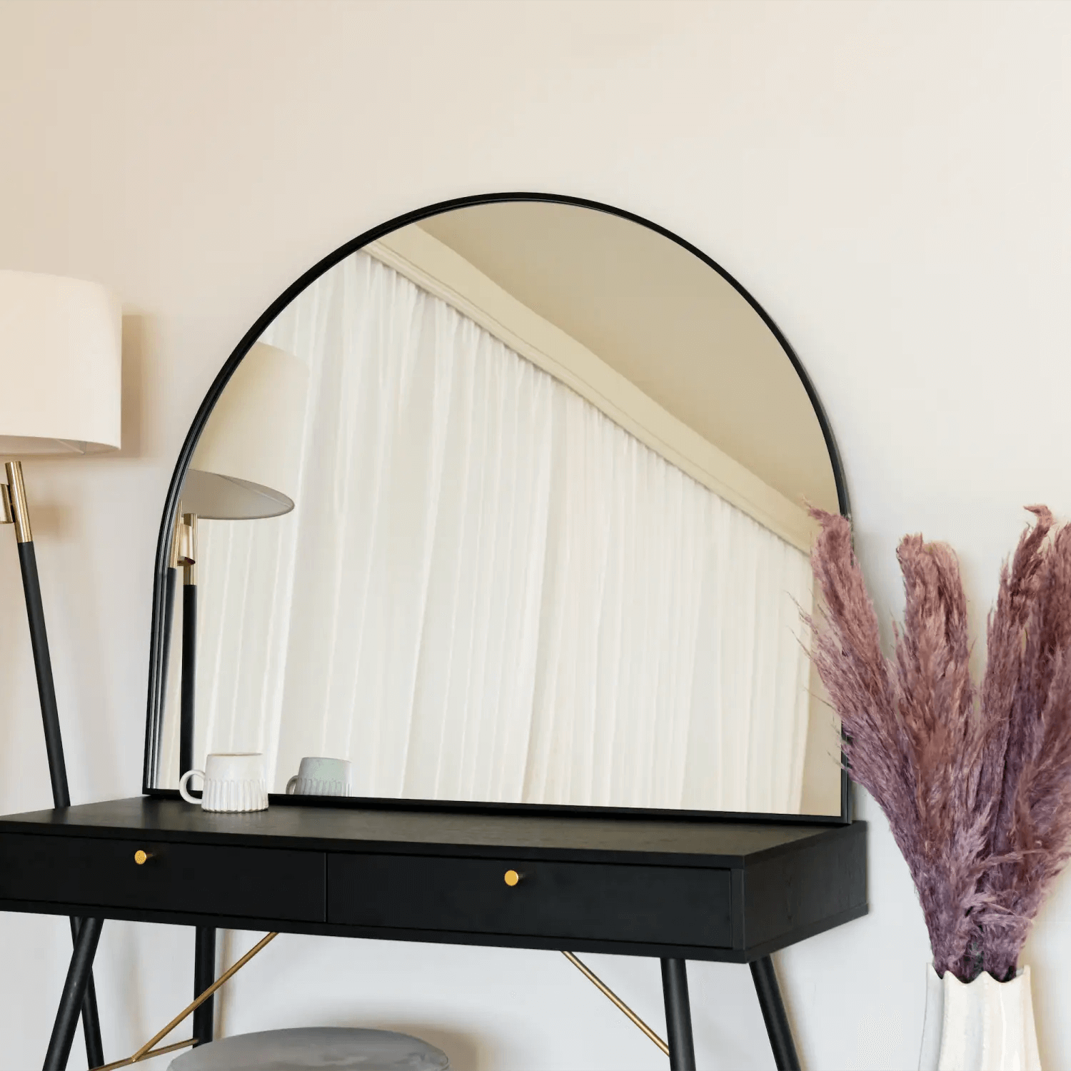 Half-circle black-framed mirror mounted on a black vanity table.