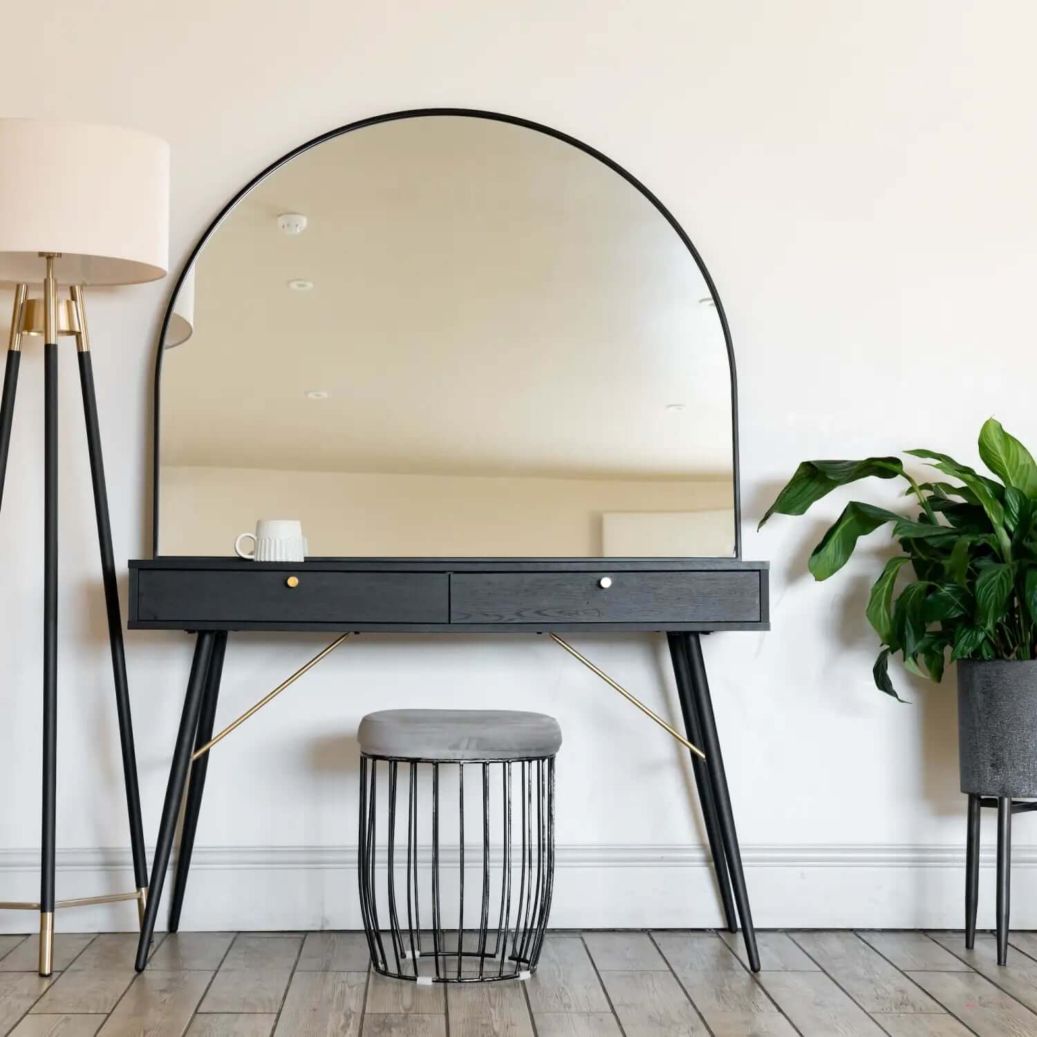 Modern black vanity table with an arched mirror and two drawers.