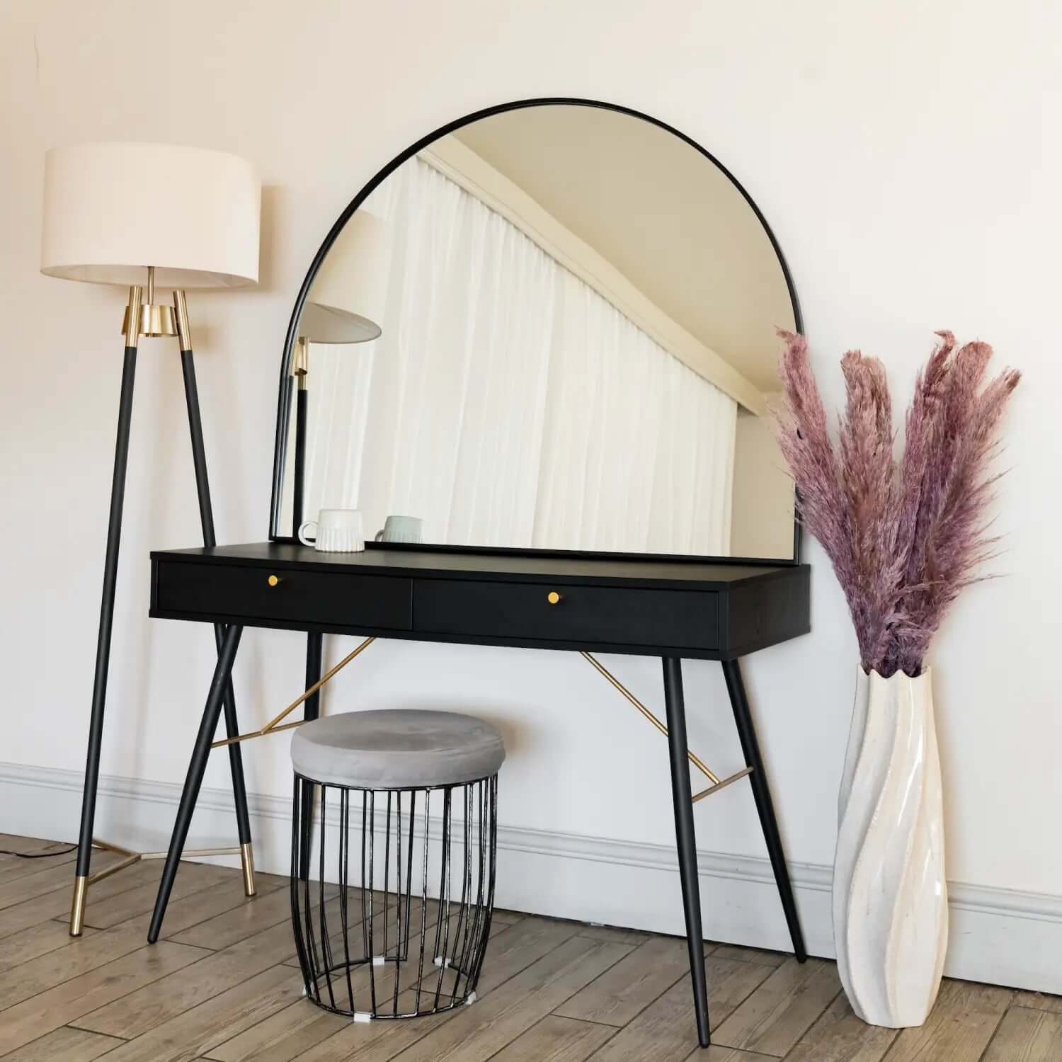 Modern black vanity desk with a round mirror and gold accents.