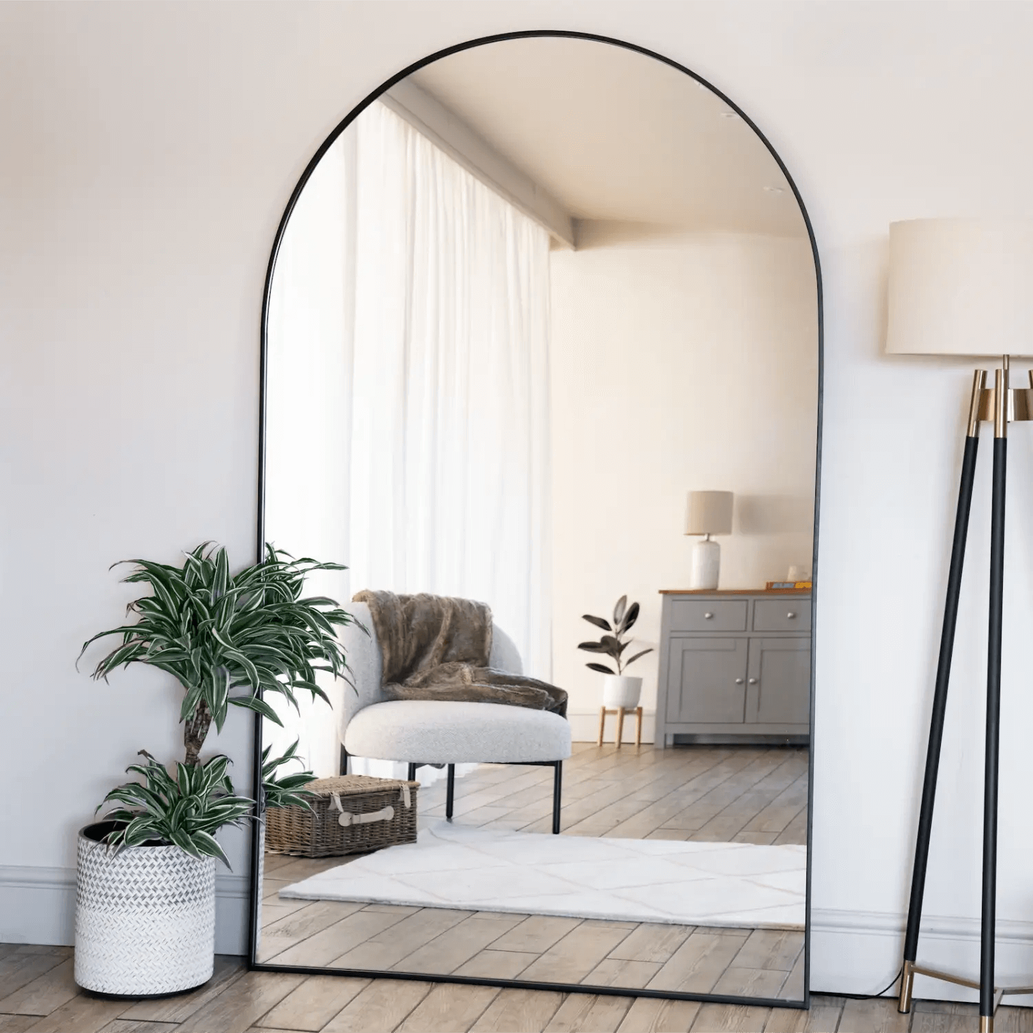 Arched floor mirror with a thin black metal frame.