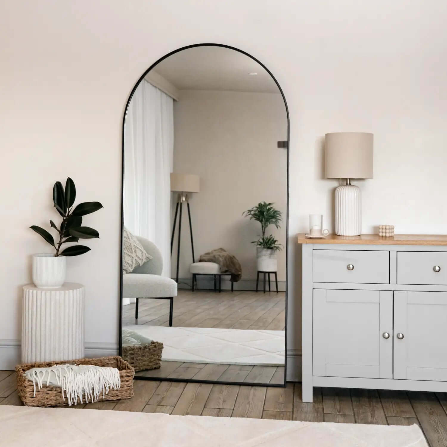 Arched black-framed floor mirror with a thin metal frame.