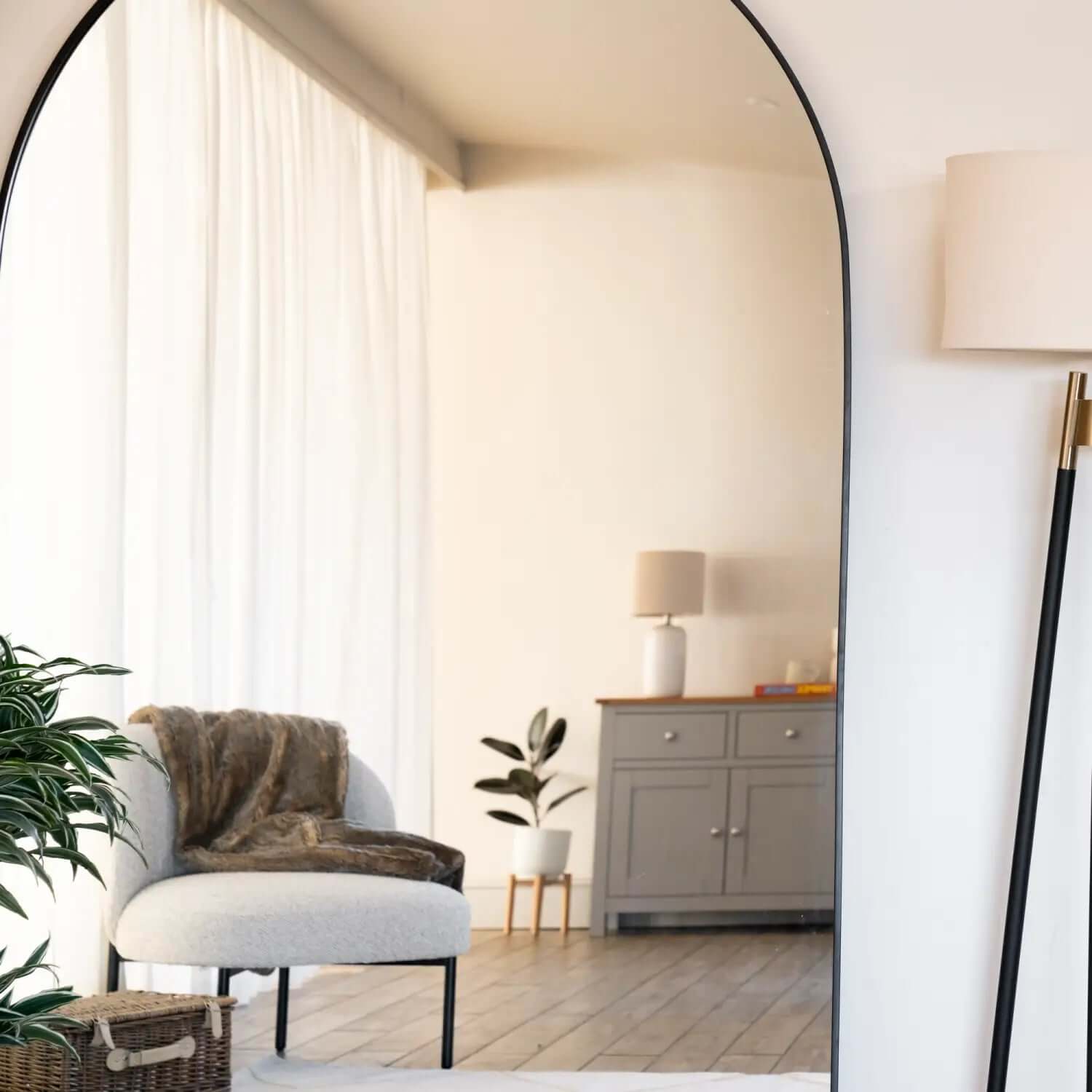 Arched black-framed floor mirror.