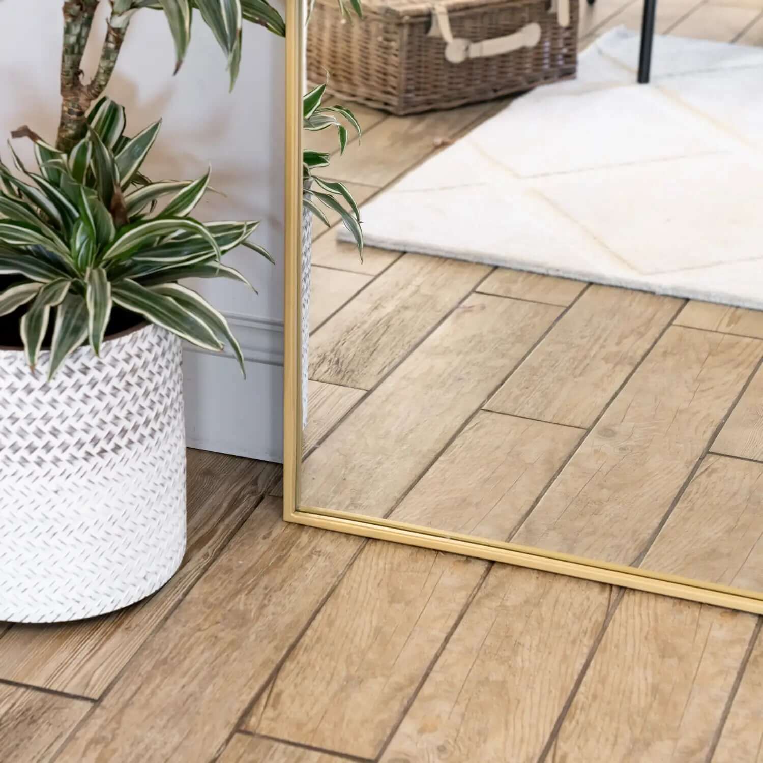 Gold-framed rectangular mirror resting on wooden flooring.