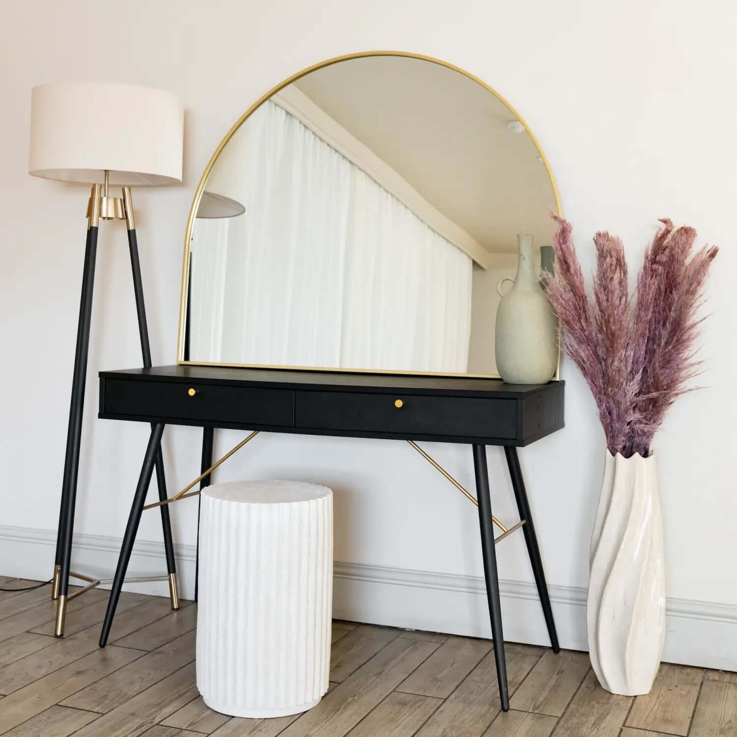 Modern black vanity desk with gold-trimmed round mirror and brass legs.