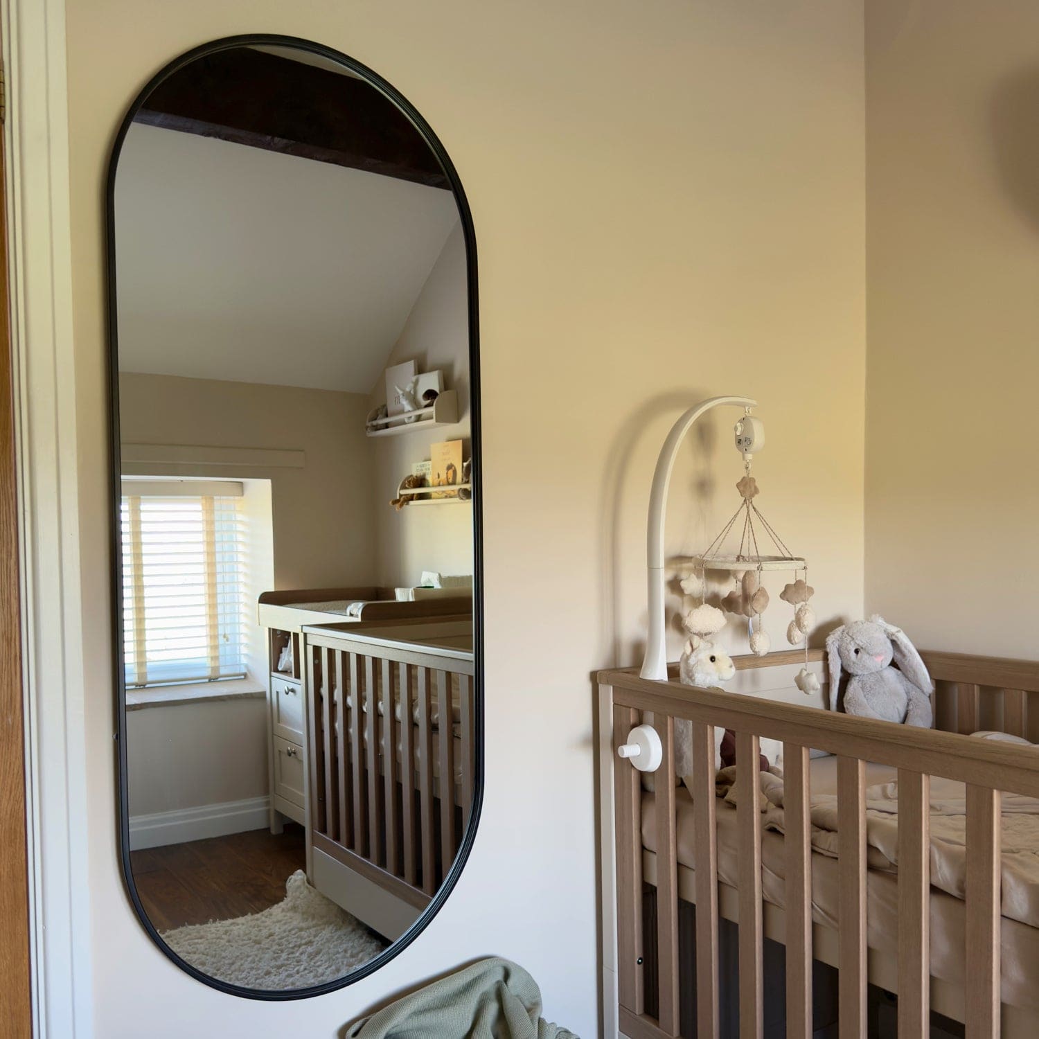 Oval-shaped wall mirror with a black frame.