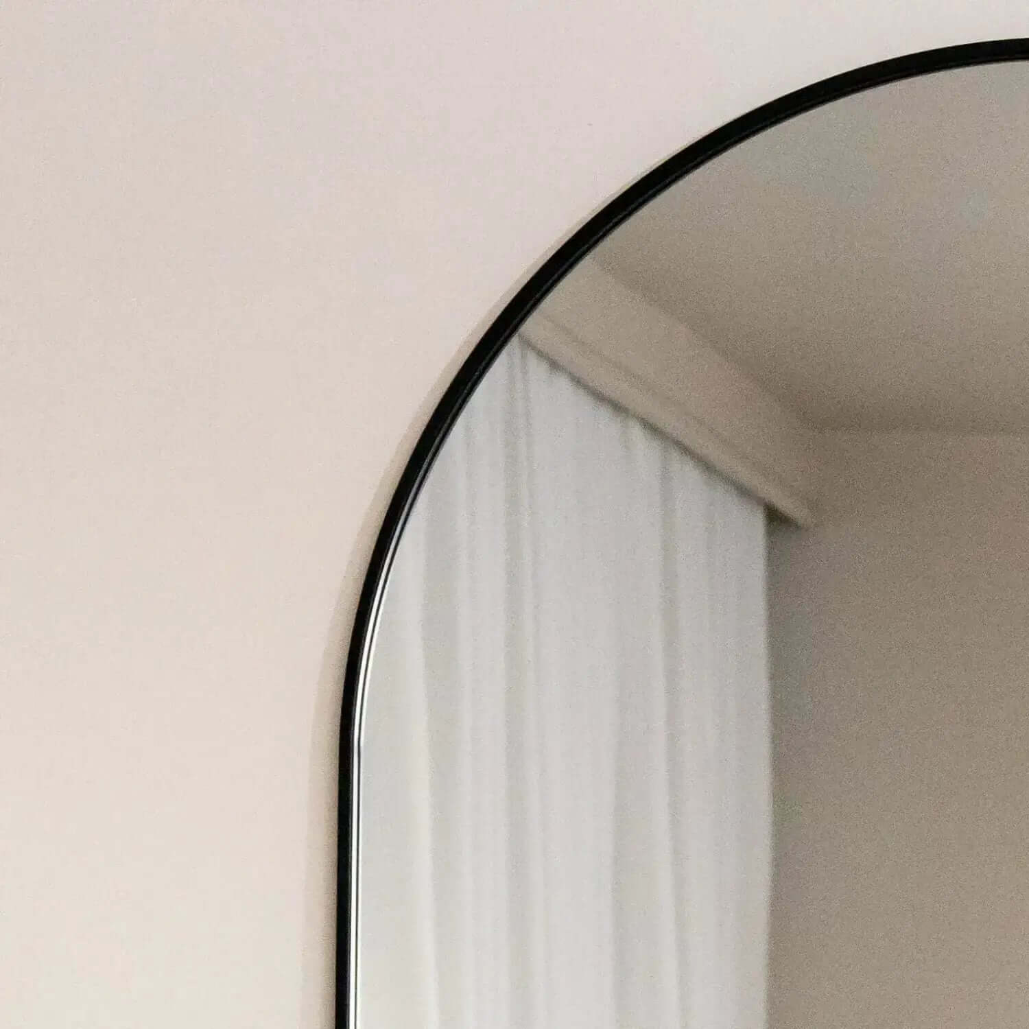 Arched mirror with a thin black metal frame.