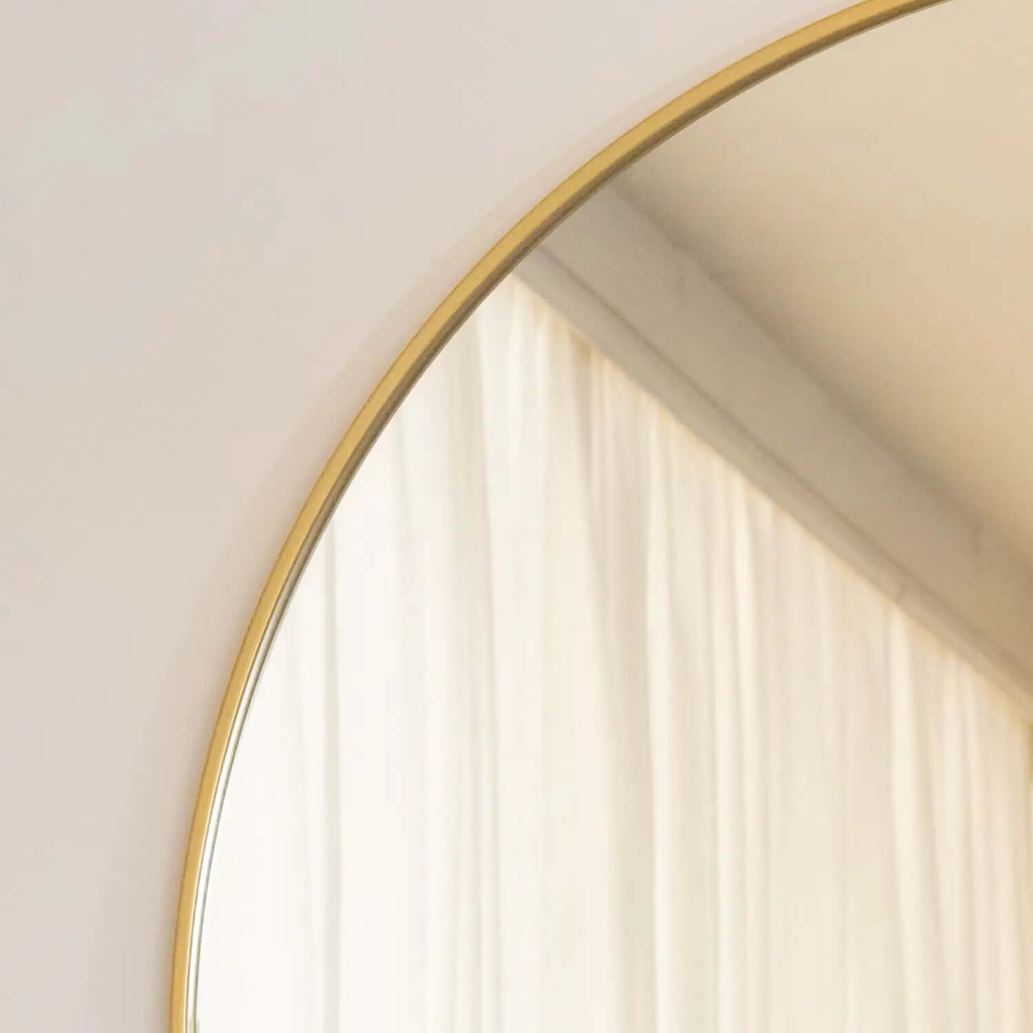 Round mirror with a thin gold frame.