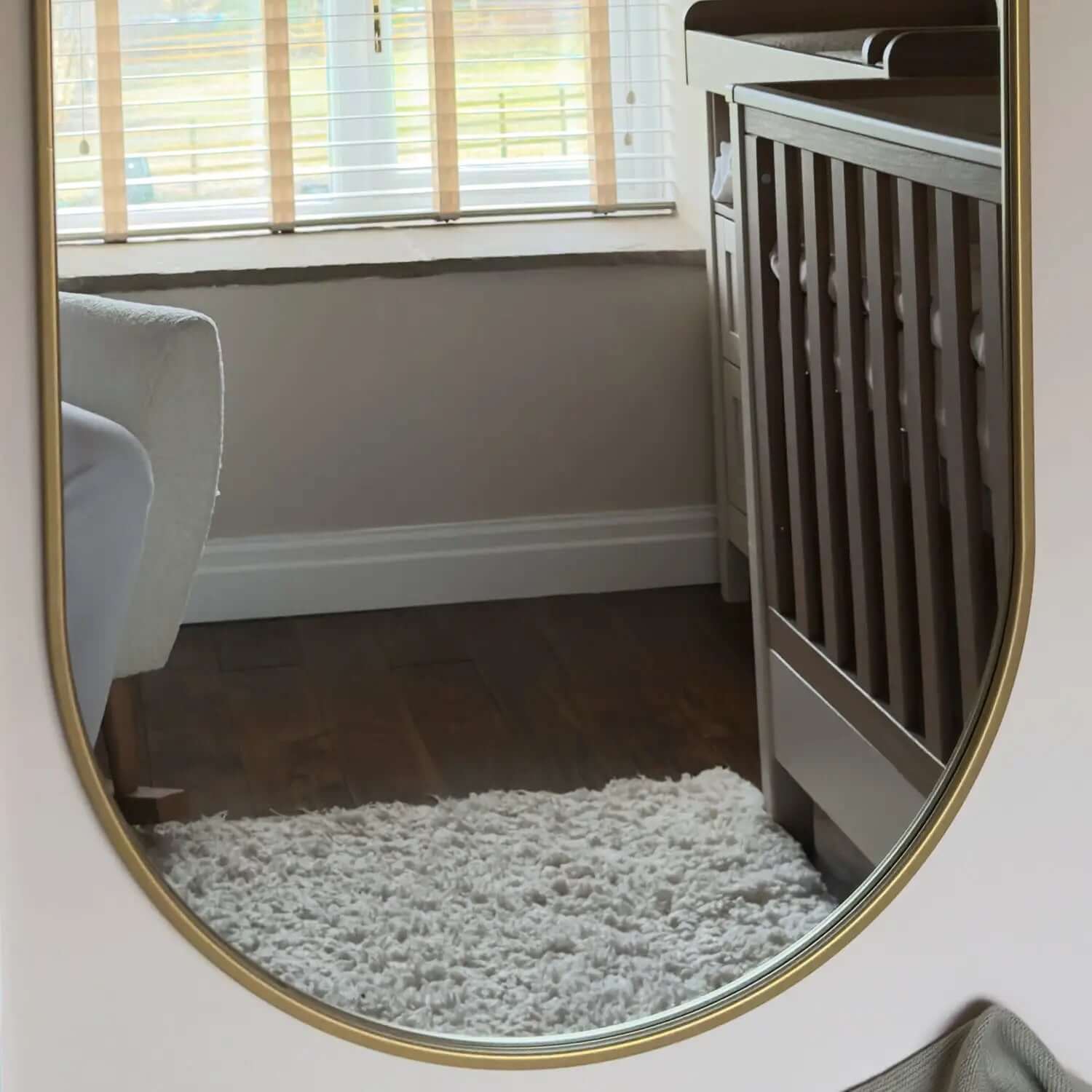 Oval mirror with a gold metallic frame.