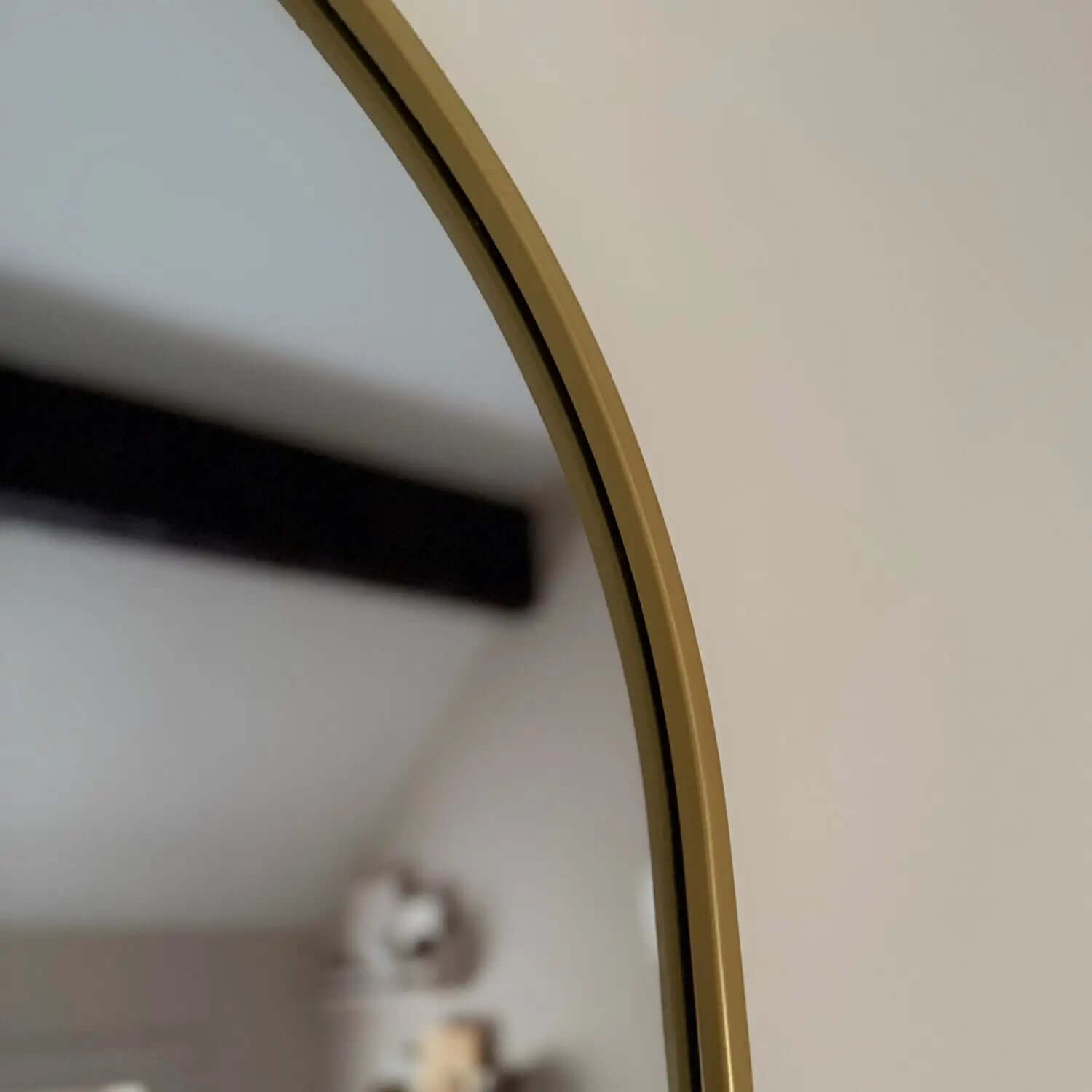 Curved edge of a round mirror with a gold-colored frame.