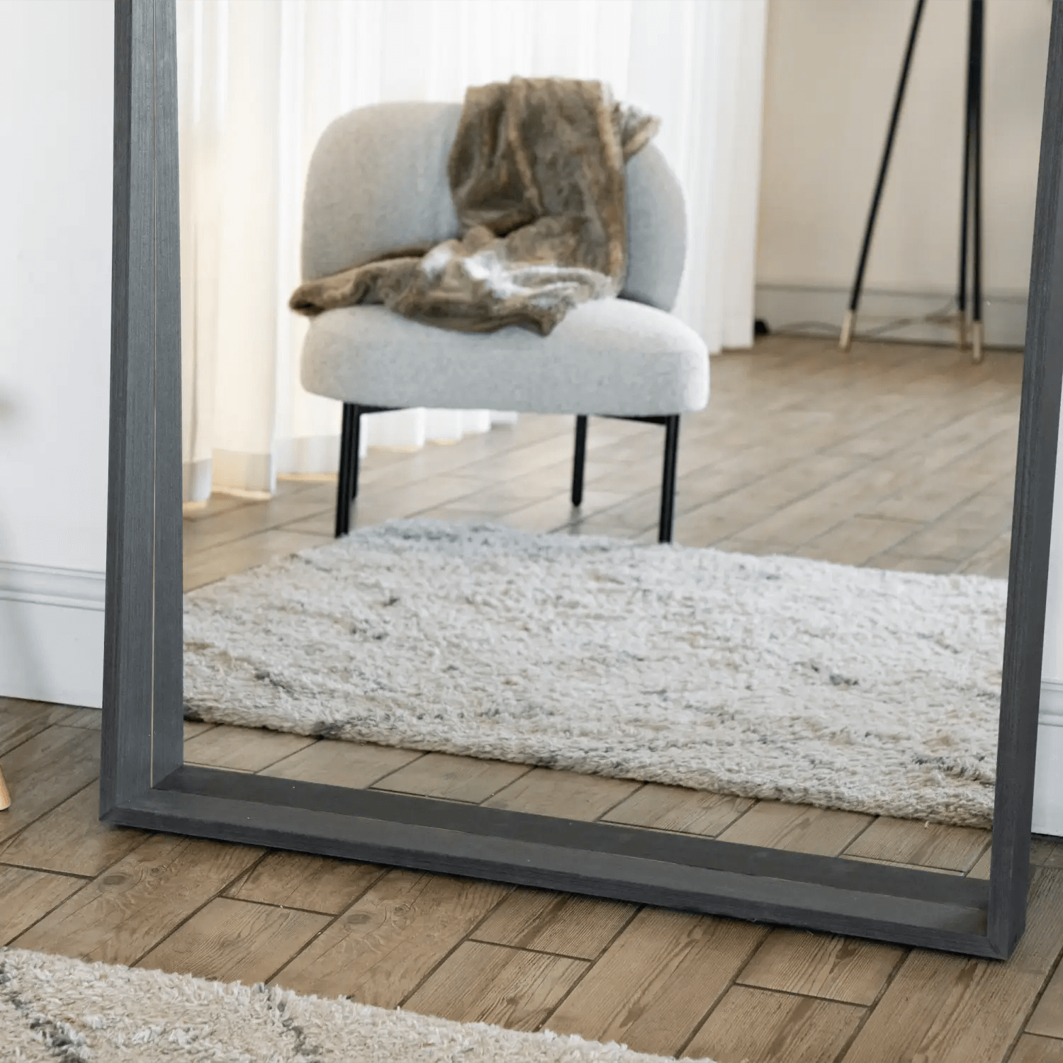 Gray-framed rectangular mirror leaning against a wall.