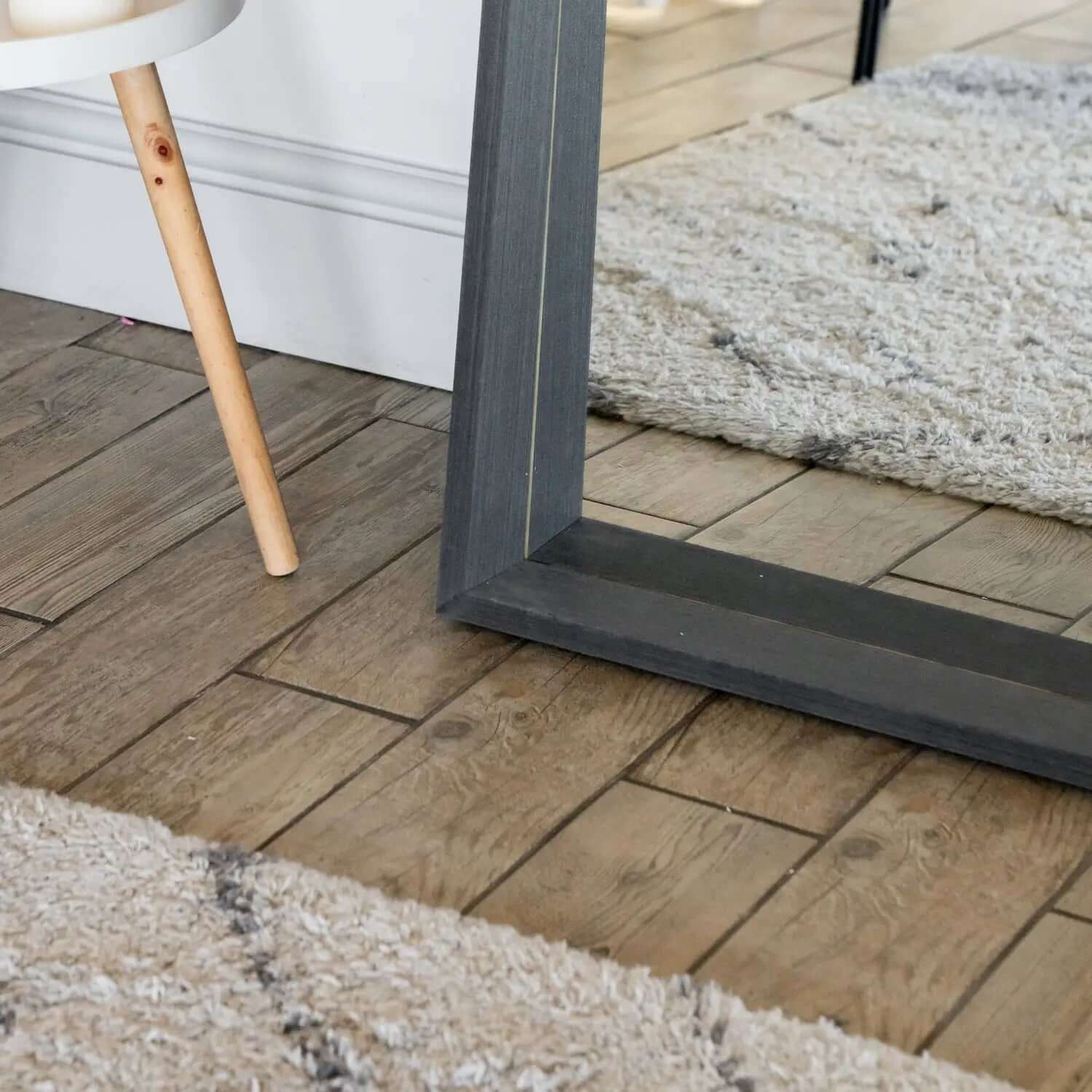 Gray-framed floor mirror with a wooden leg support.