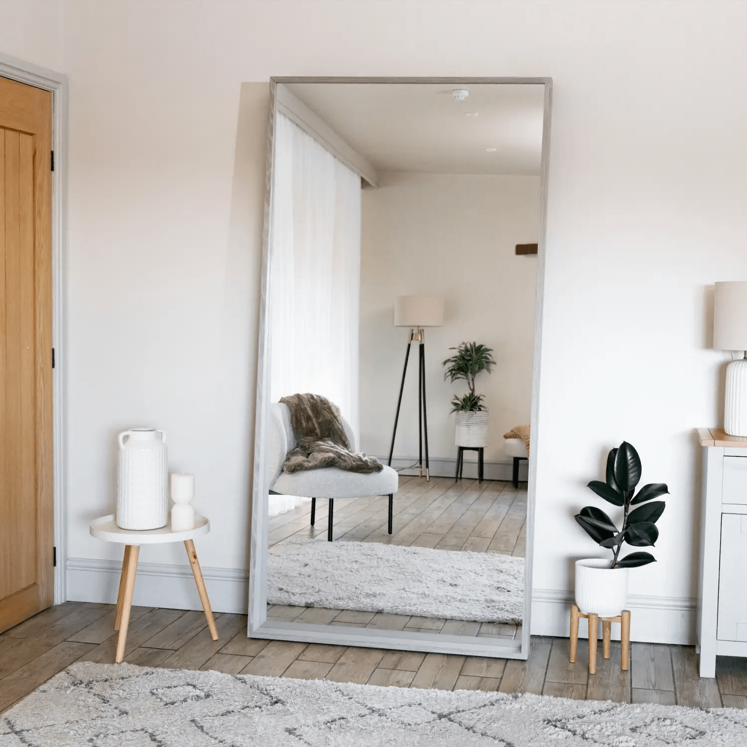 Floor-length silver-framed mirror leaning against a wall.