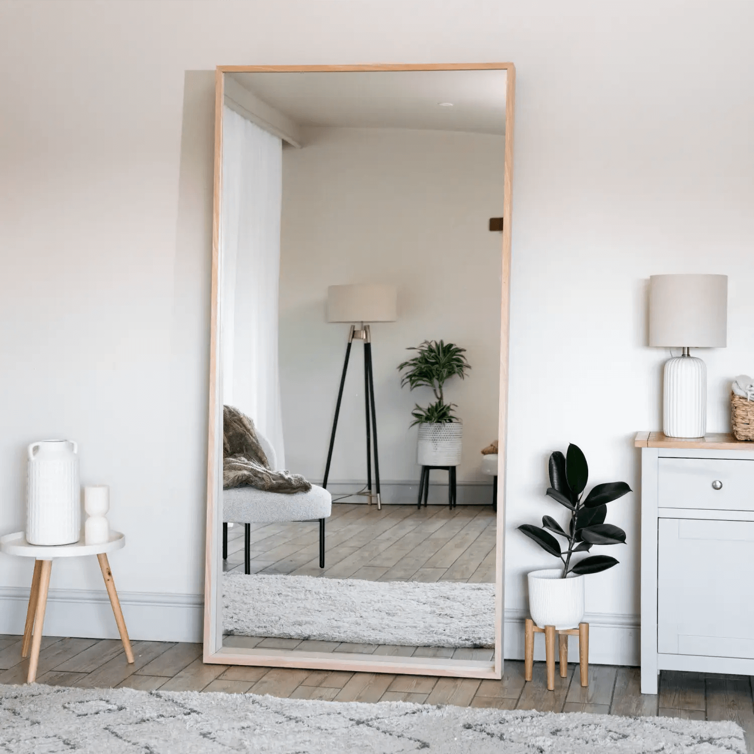 Floor-length mirror with a light wooden frame.