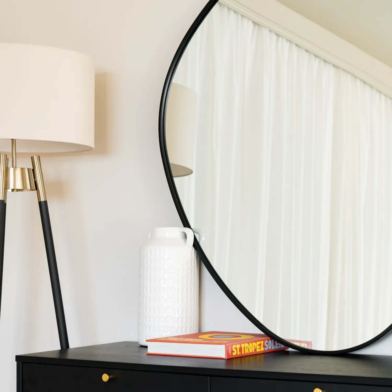 Round black-framed mirror mounted on a wall.