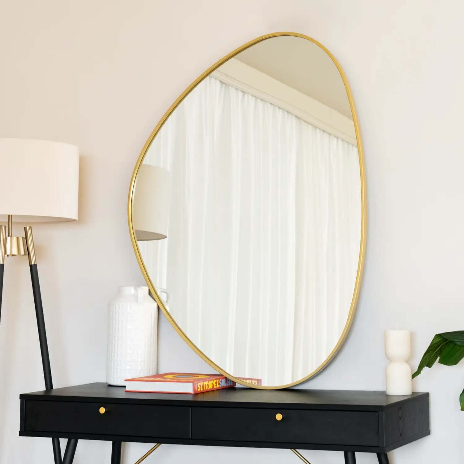 Irregularly-shaped mirror with a thin gold frame.