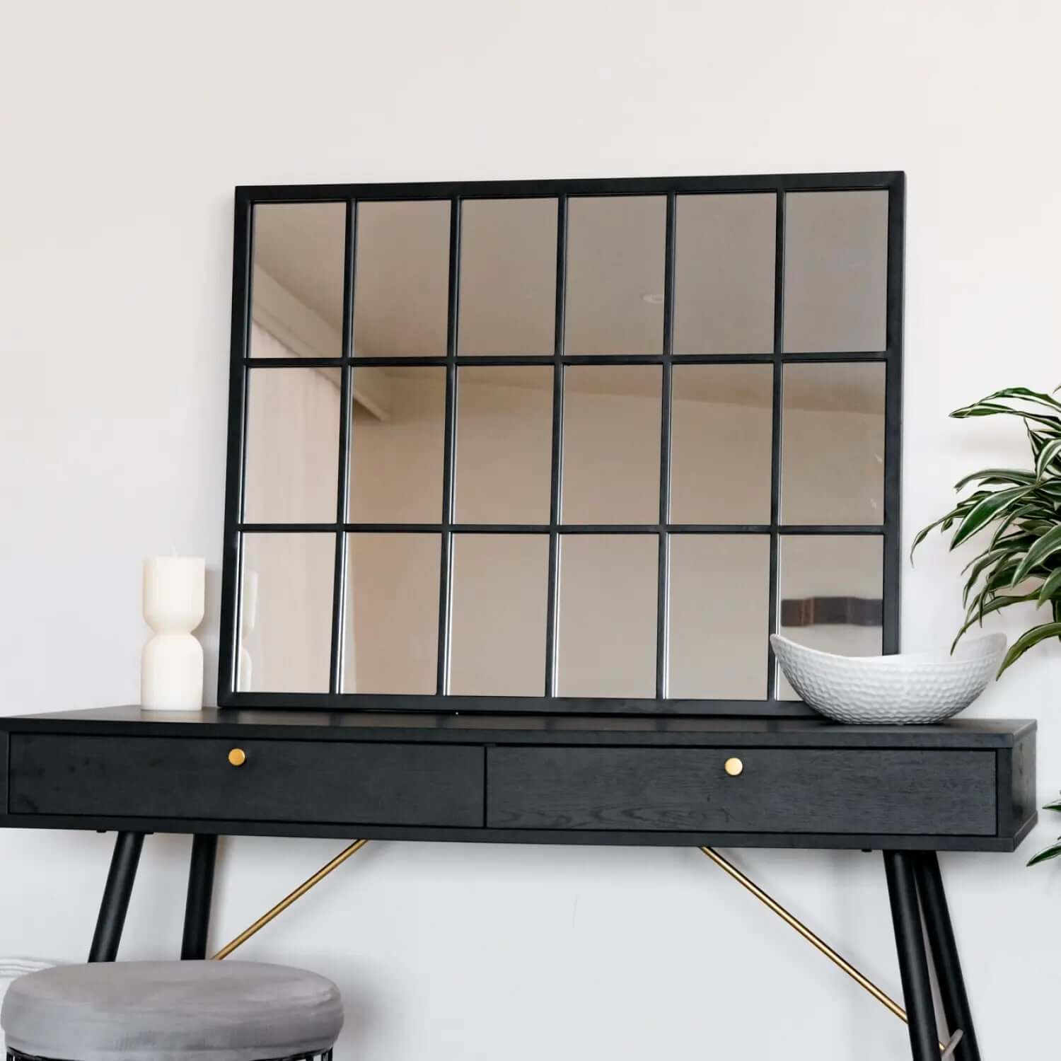 Black-framed window-pane style mirror mounted above a modern console table.