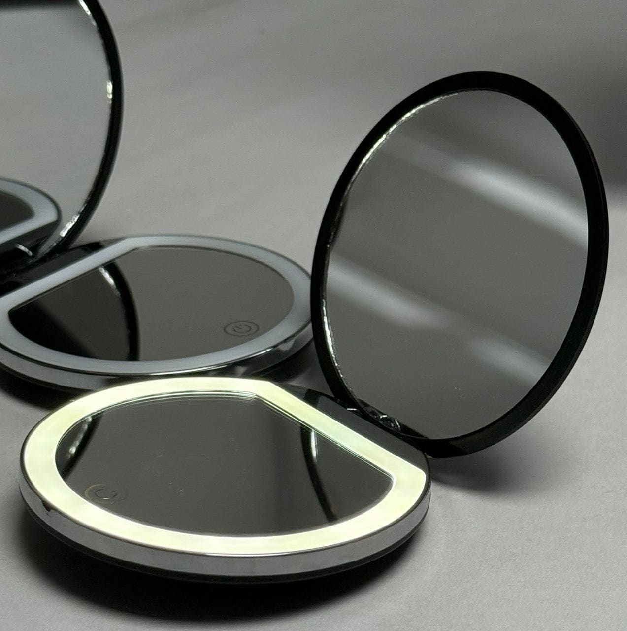 Compact mirror with illuminated edge, black and silver design.