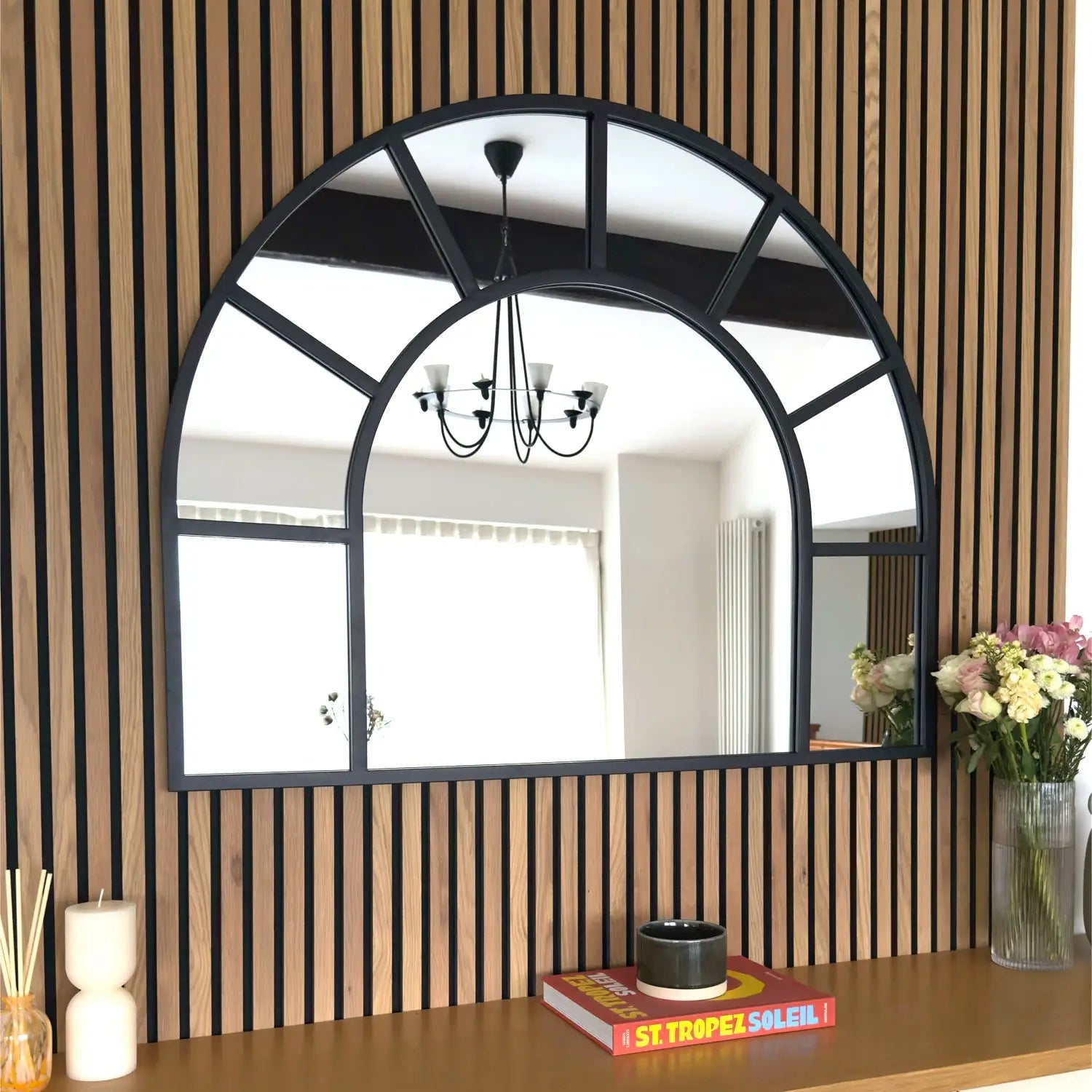 Arched window-style mirror with black metal frame dividers.