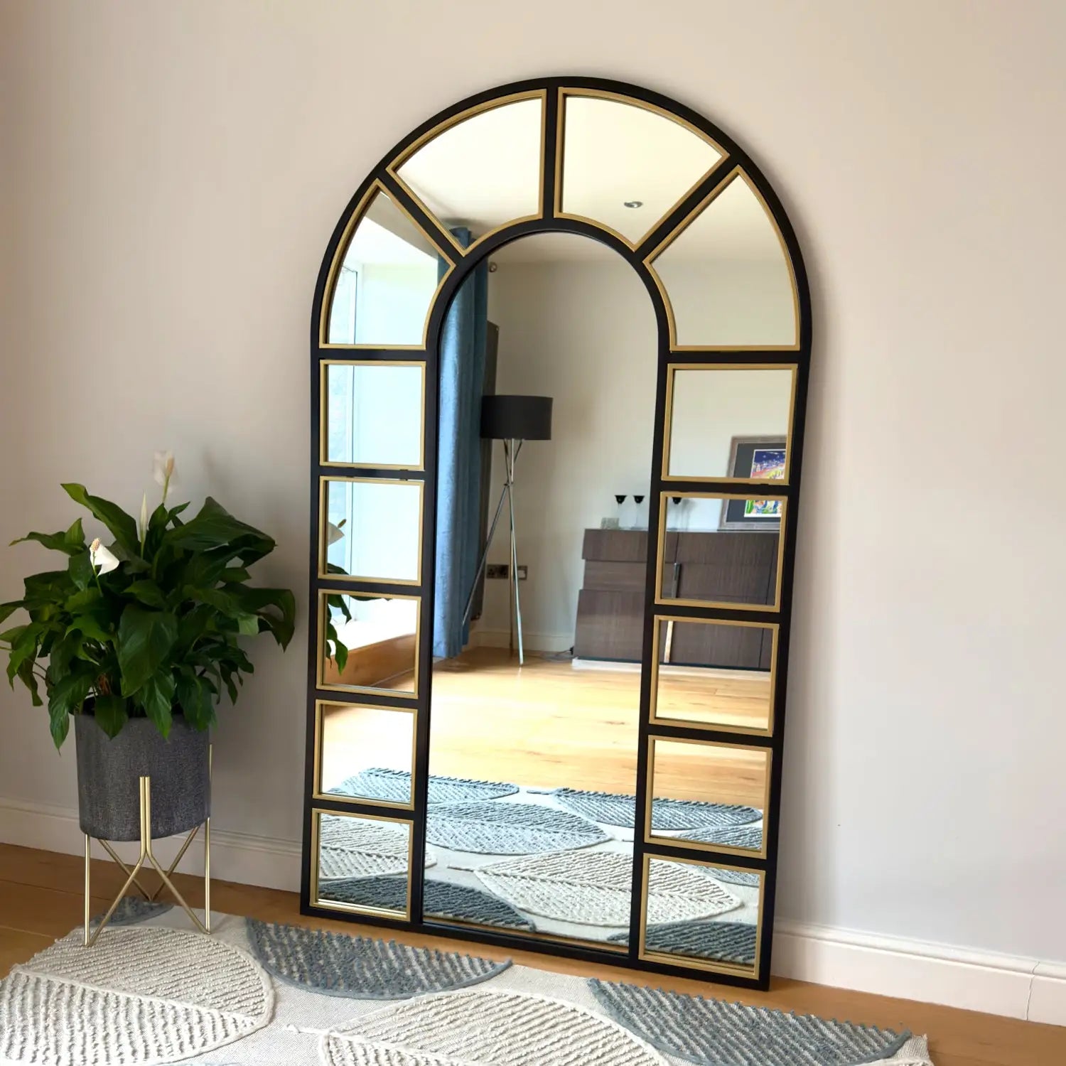 Arched, paneled mirror with black and gold trim.