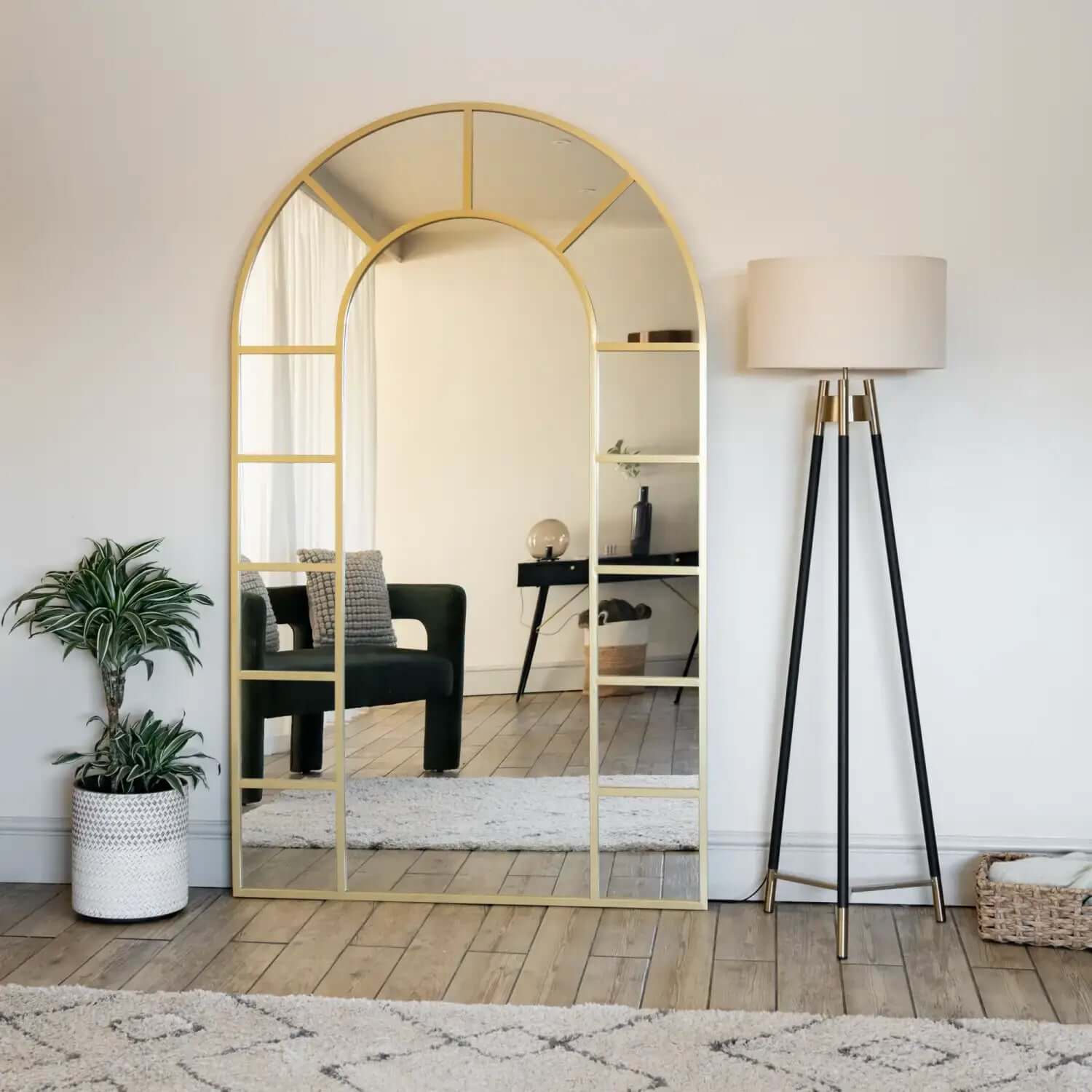 Arched gold-framed floor mirror with geometric pane details.