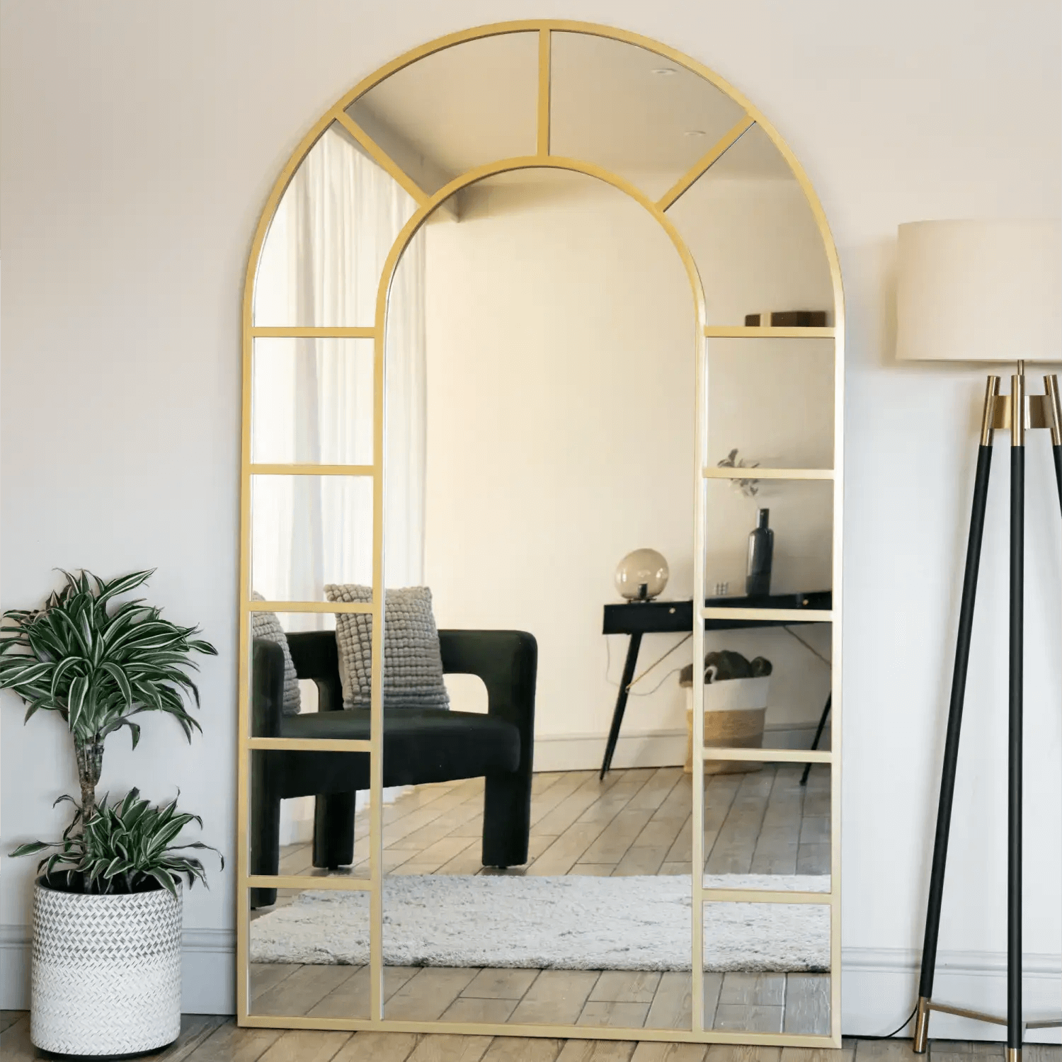 Arched gold-framed floor mirror with geometric panel details.