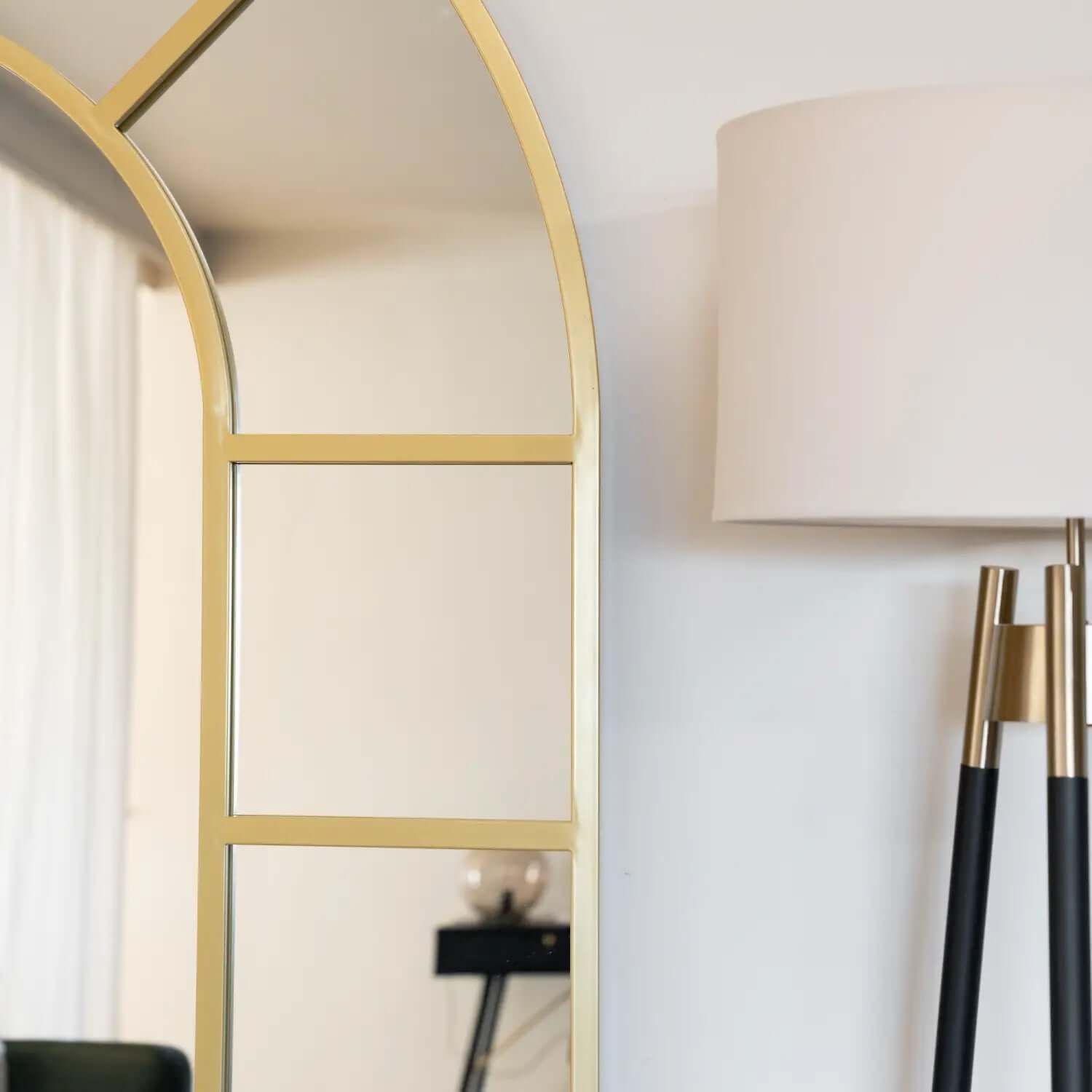 Arched gold-framed mirror with geometric panel details.