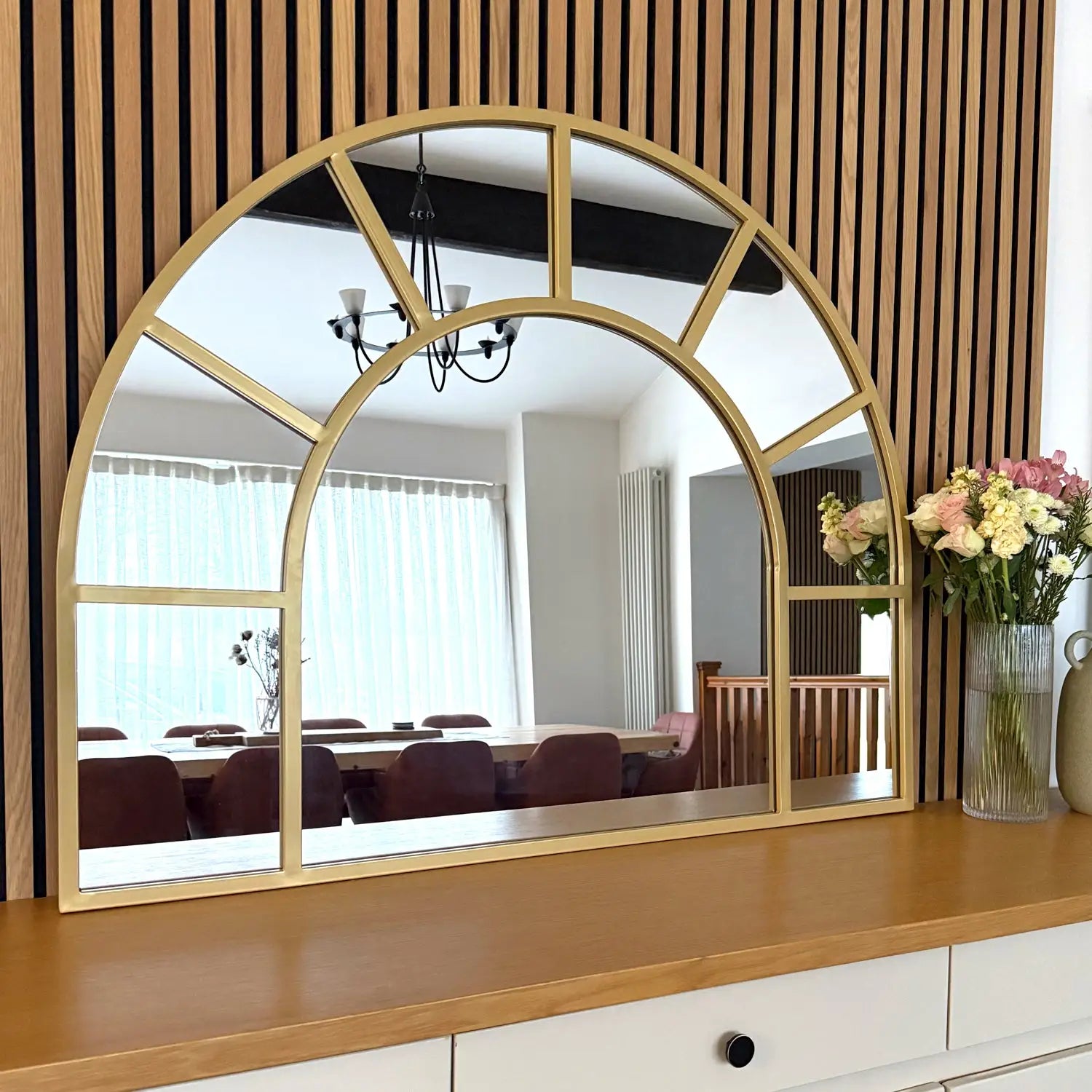 Gold-framed arched mirror with divided panes.