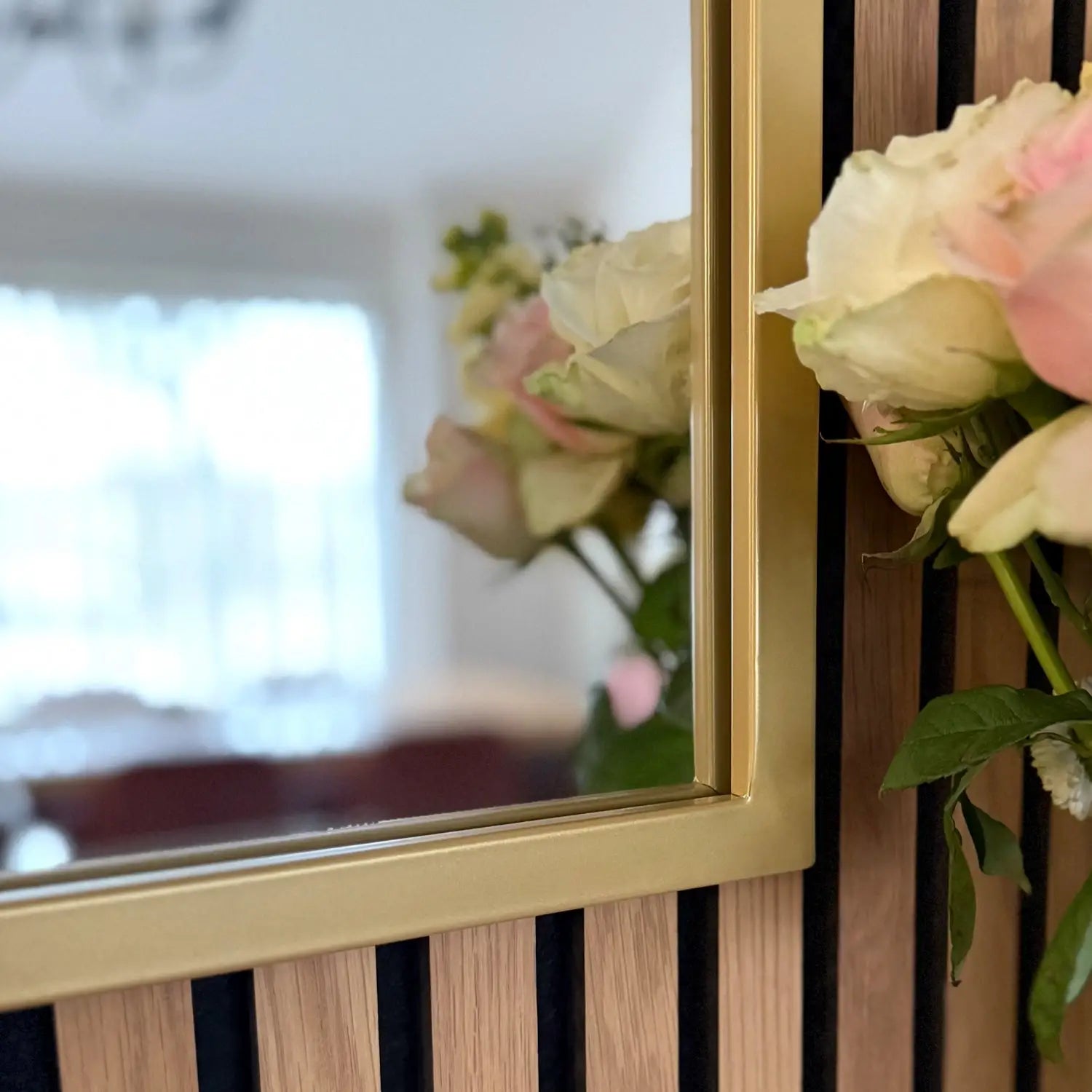 Pink and white roses beside a framed mirror.