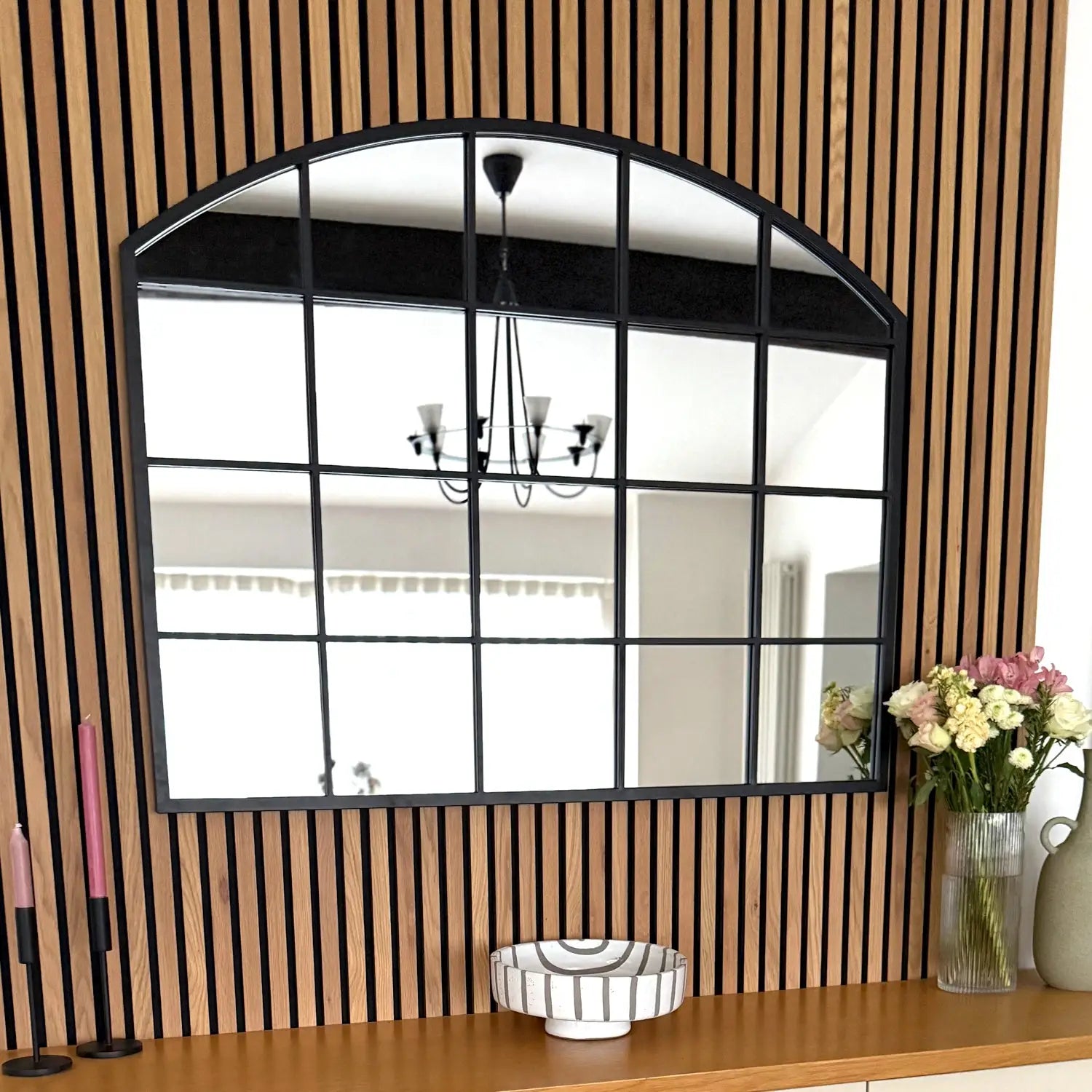 Arched window-style mirror with black grid pattern framing.